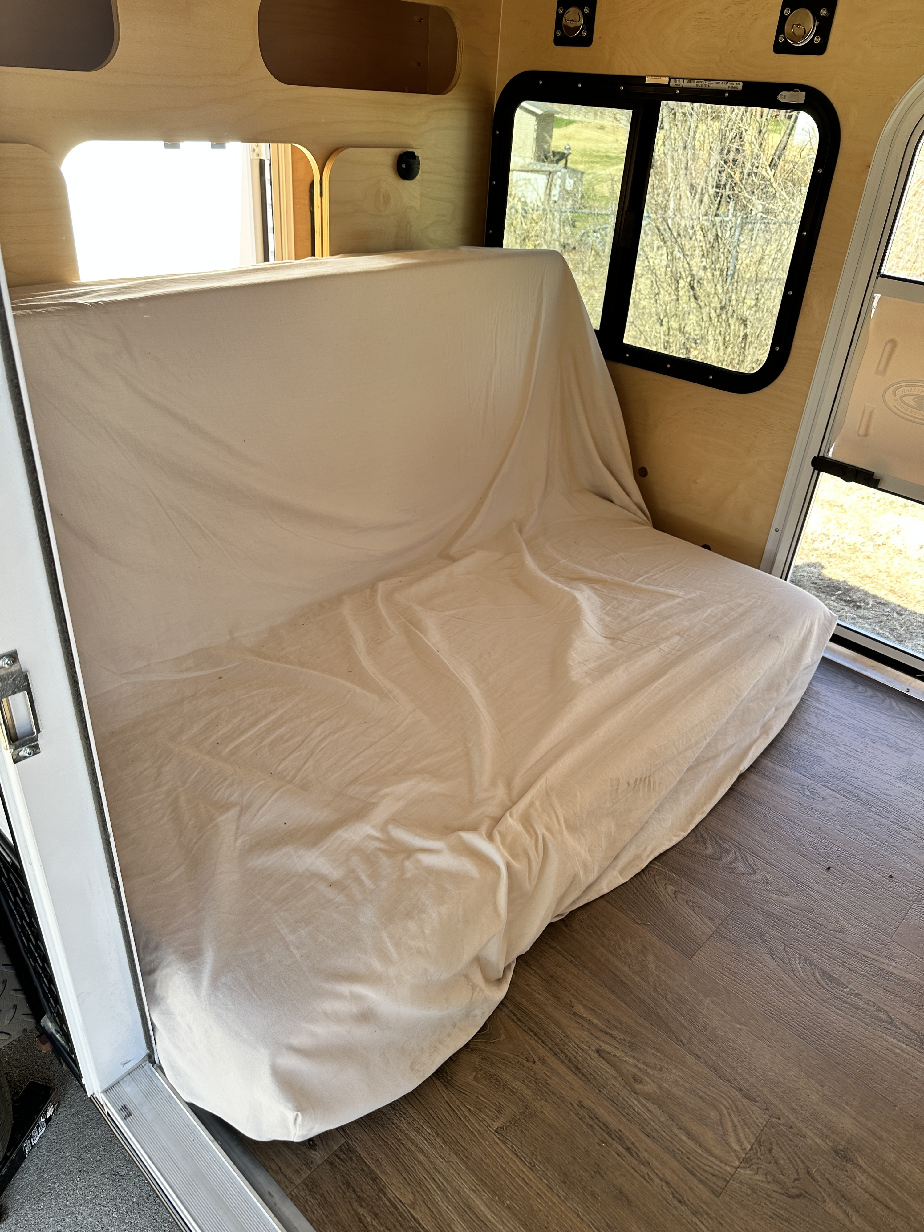 RV rental interior: A light-colored bench-style bed with wood paneling, windows, and wood-look floor.. Hiker HD580 2022