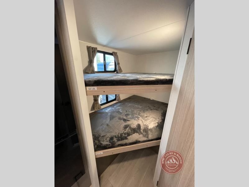 RV rental interior features bunk beds for extra sleeping space. Two bunks, visible windows, and light wood tones define this cozy area.. KZ Sportsmen Select 2026