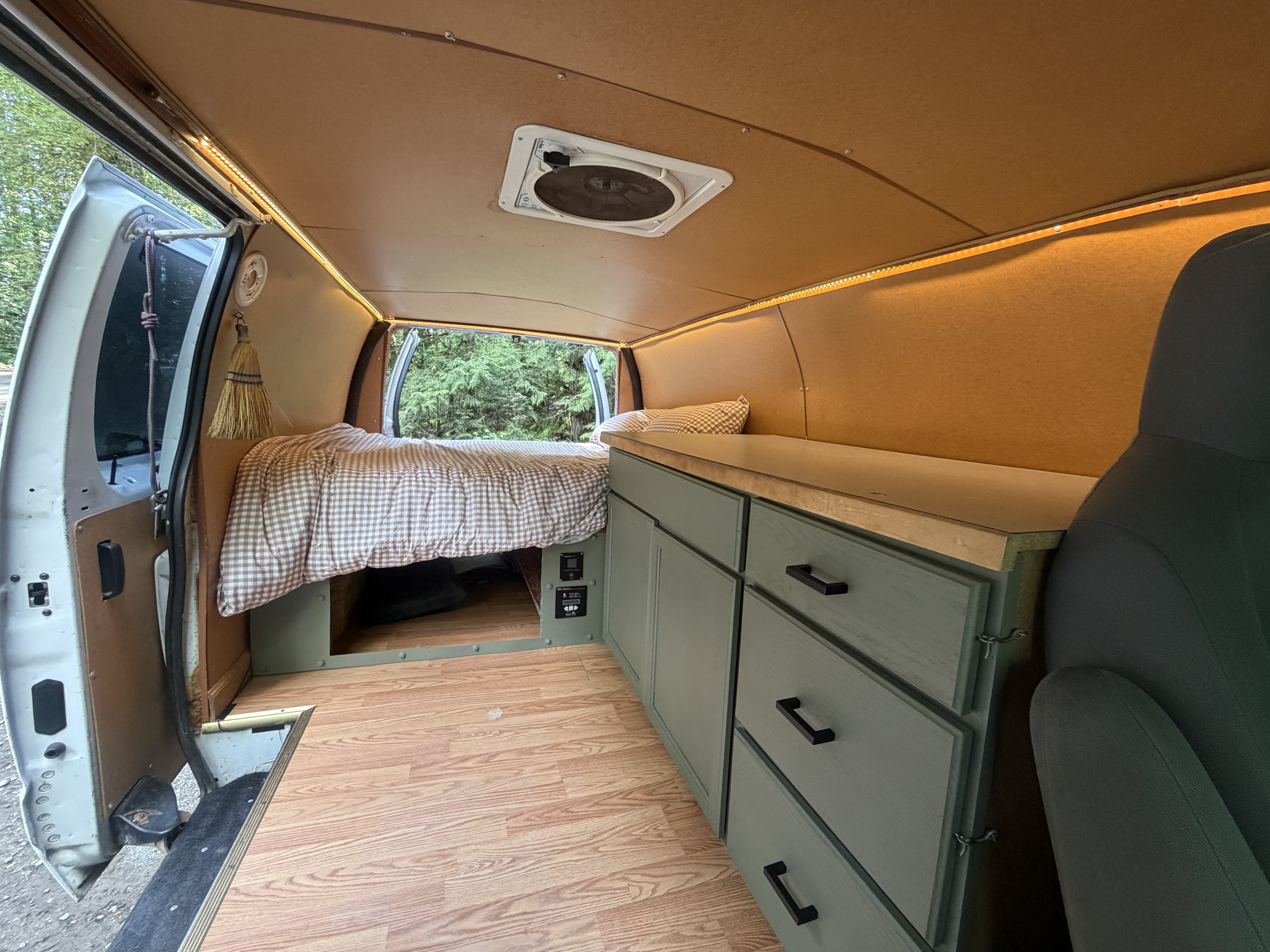 Explore nature in this RV rental! Custom van interior features a comfy bed, green cabinets, wood floor, and LED lights.. Ford Econoline 2010