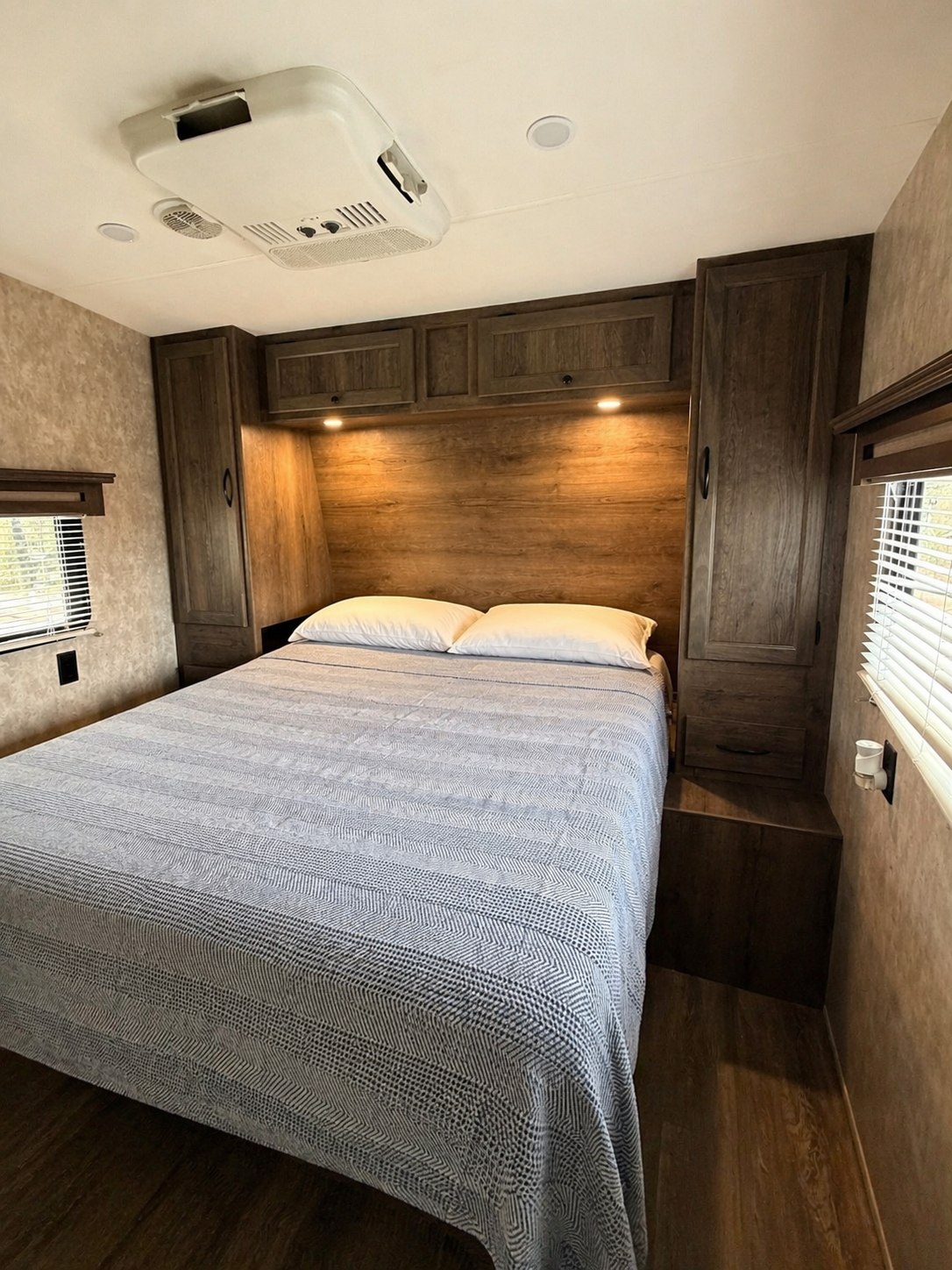 Cozy RV rental bedroom with patterned bedspread, ample overhead storage, and AC unit for your next adventure.. Eclipse Recreational Vehicles Iconic 2017