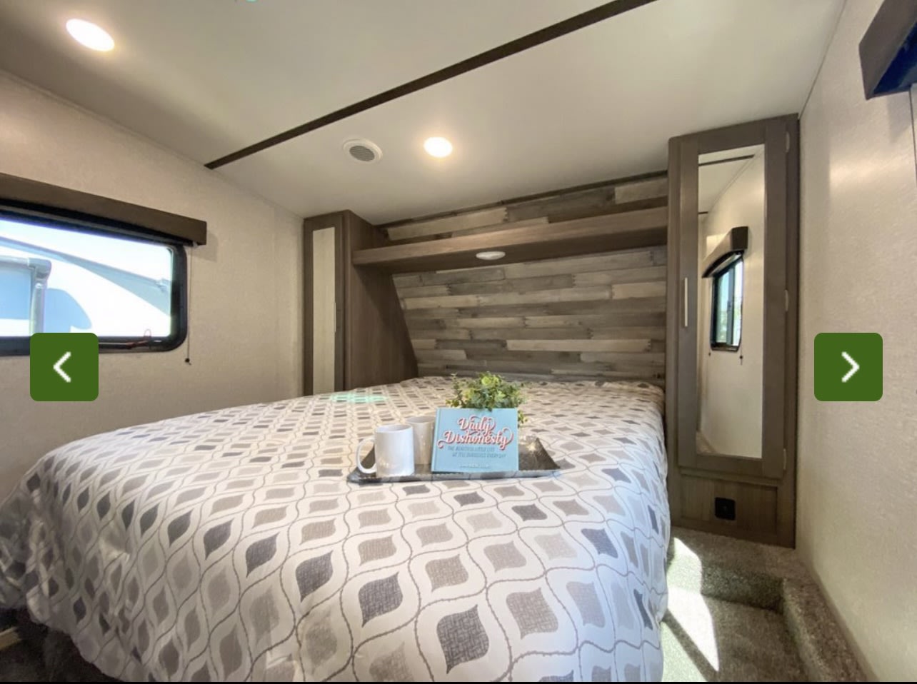 Cozy RV rental bedroom interior: comfy bed with wood-paneled headboard, window, and mirrored closet for a relaxing stay.. Crossroads RV Volante 2021