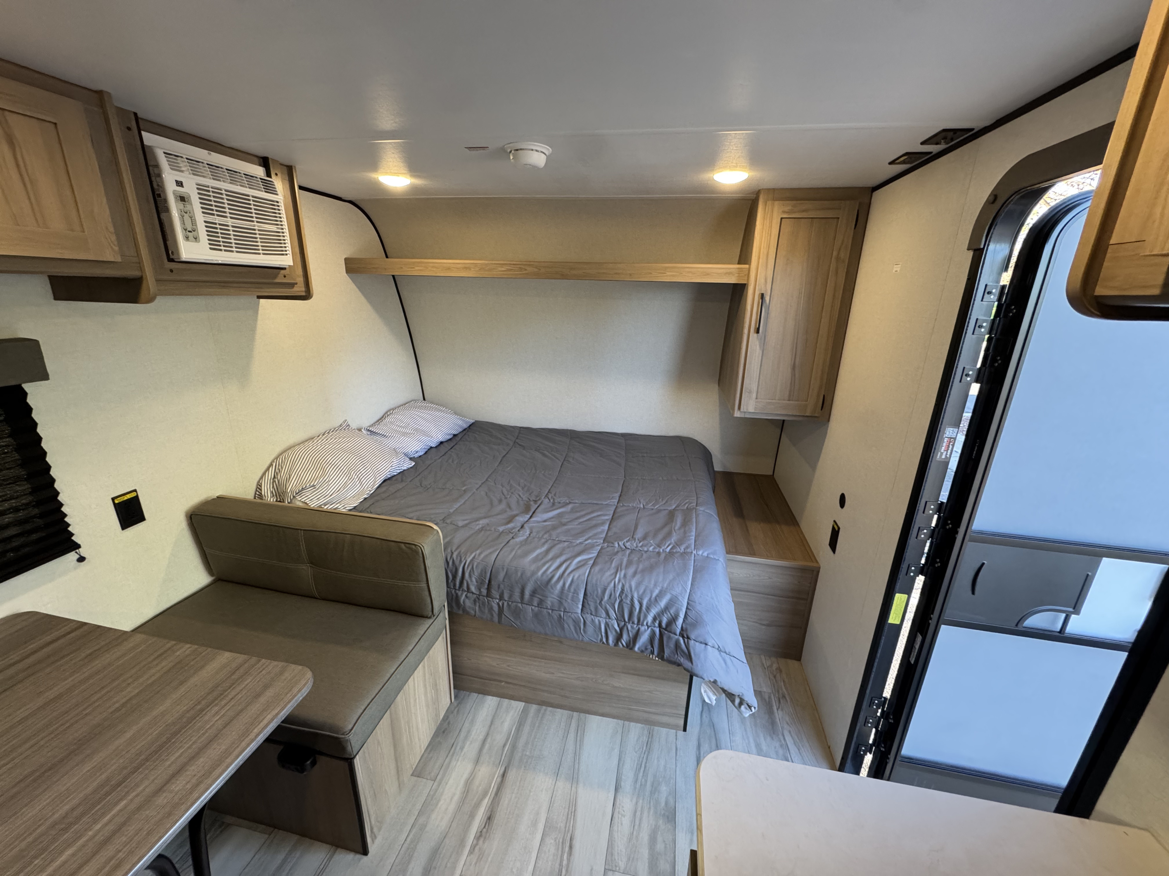 Cozy rv rental bedroom with a bed, dinette, AC unit, and light wood cabinetry. Perfect compact RV interior for travel.. Coleman Coleman 17B 2026