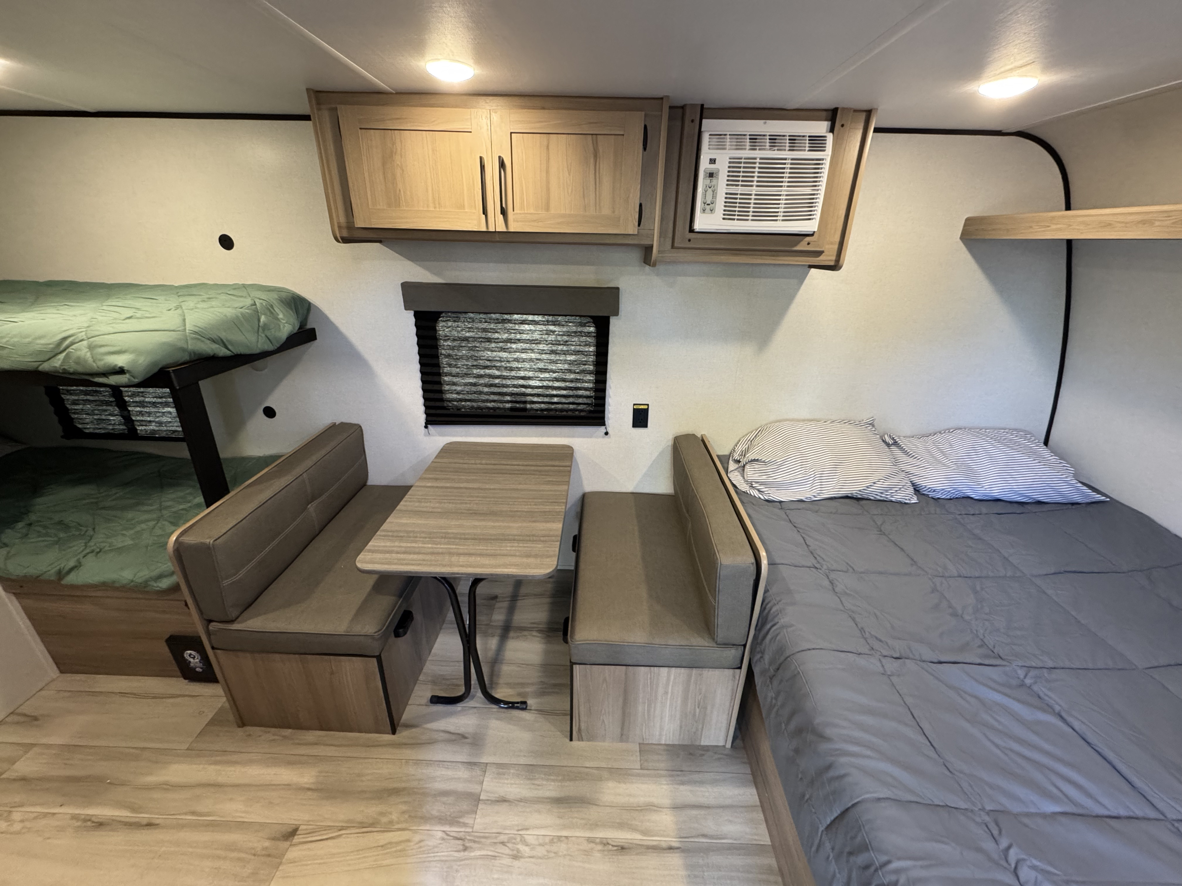 Cozy rv rental interior with bunk beds, a dinette, main bed, and AC unit. A compact, functional space for travel.. Coleman Coleman 17B 2026