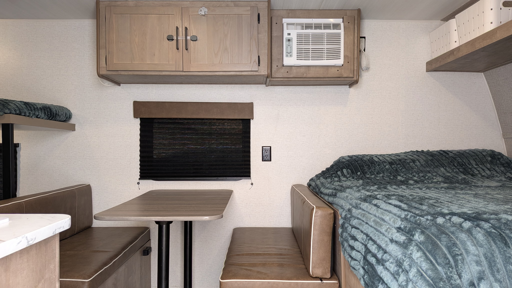 RV rental interior: Dinette, bunk bed, AC unit, and bed with green blanket. Functional compact living space.. Keystone RV Springdale Mini 2025
