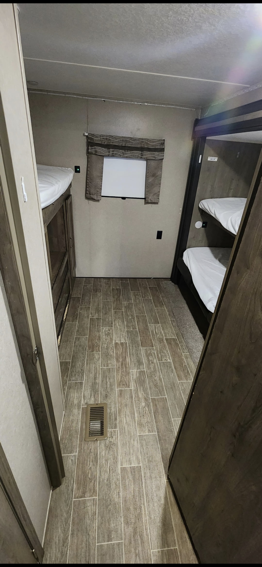 Inside this RV rental: a comfortable bunkhouse area with two sets of beds, wood-look flooring, and a window.. Forest River Palomino Puma 2020