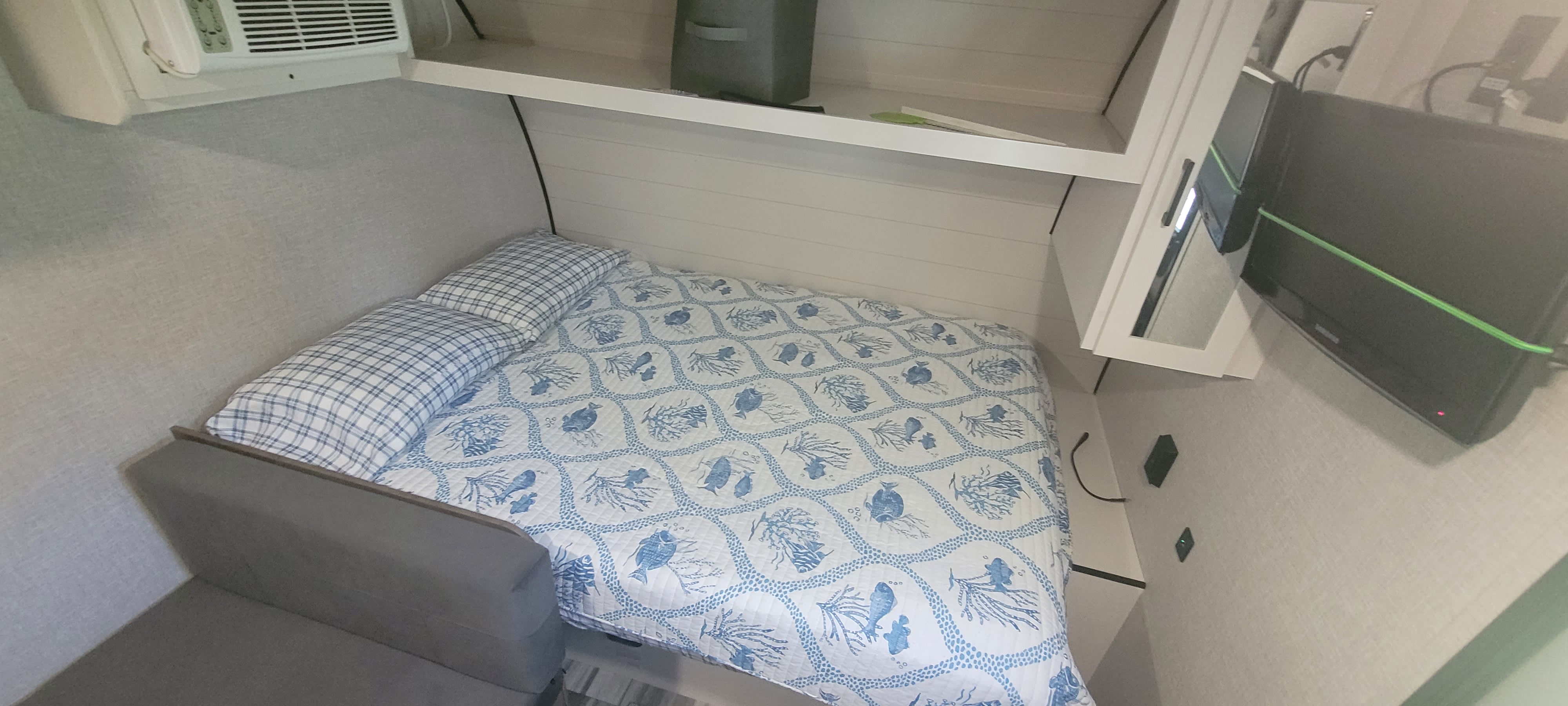 Experience comfort in our RV rental! This cozy sleeping area features a bed with marine-themed quilt, AC, TV, and shelves.. Jayco Jay Flight SLX 2025