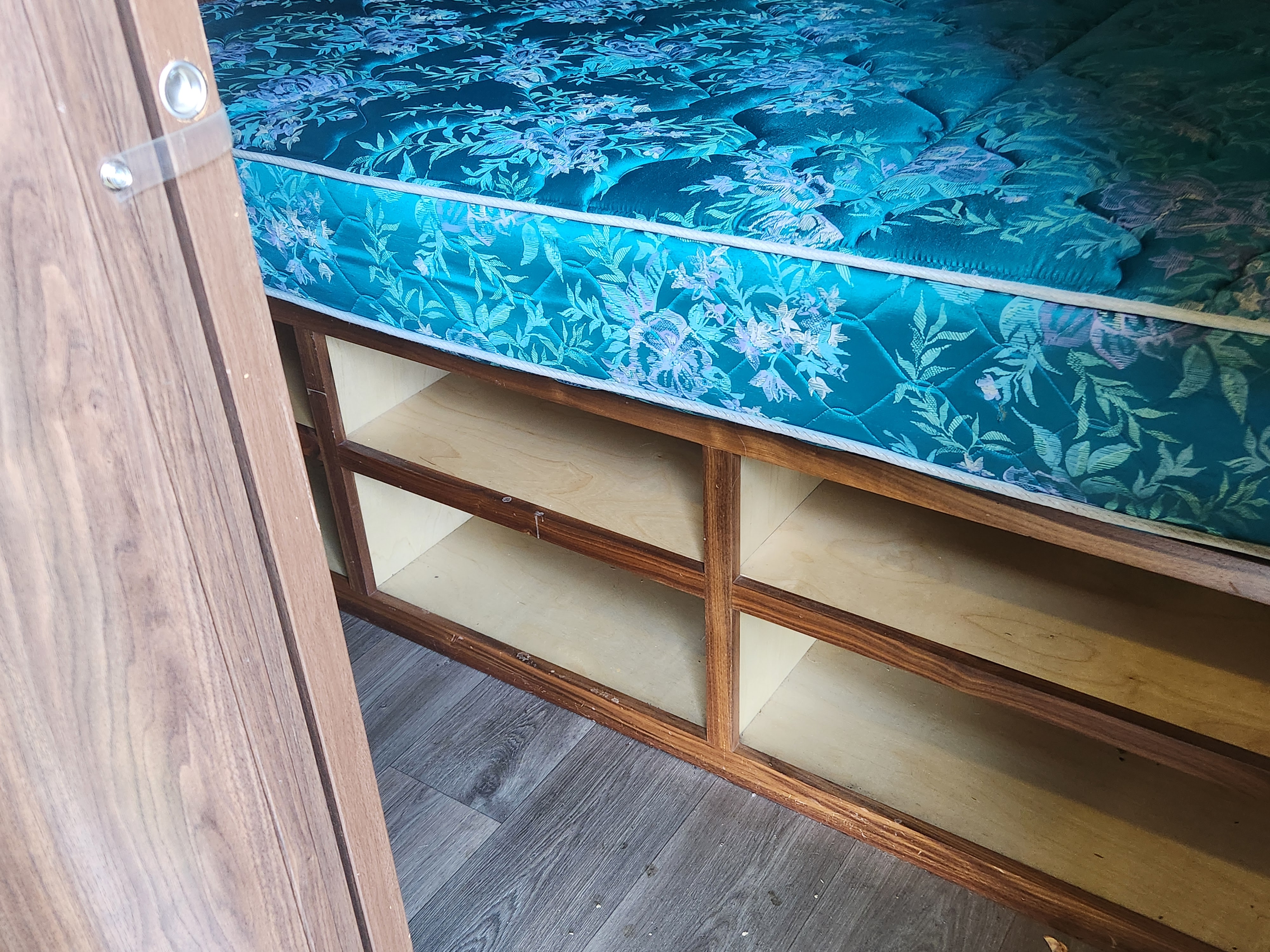 RV rental: Teal floral mattress atop built-in wooden under-bed storage, providing practical space in a compact camper.. Coleman 2855bh 2016