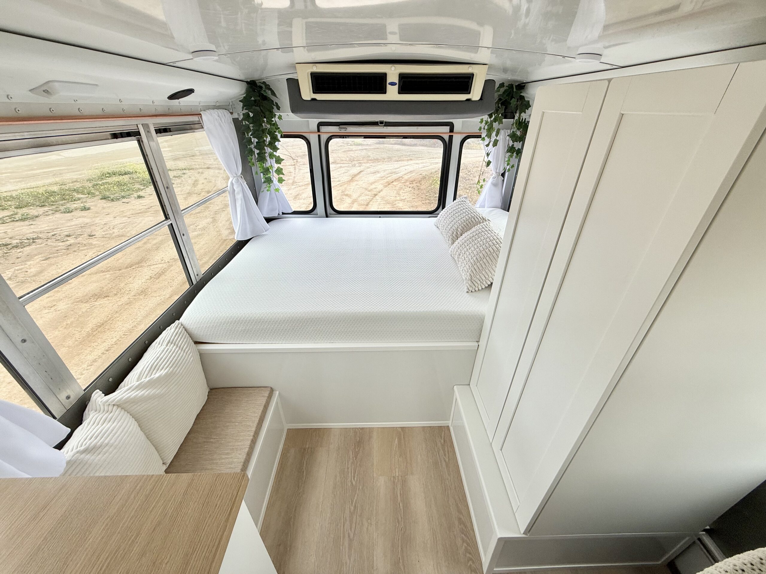 Modern RV rental interior with a plush bed, windows, and clean white design. Ideal for a comfortable road trip experience.. Chevy Express 2007