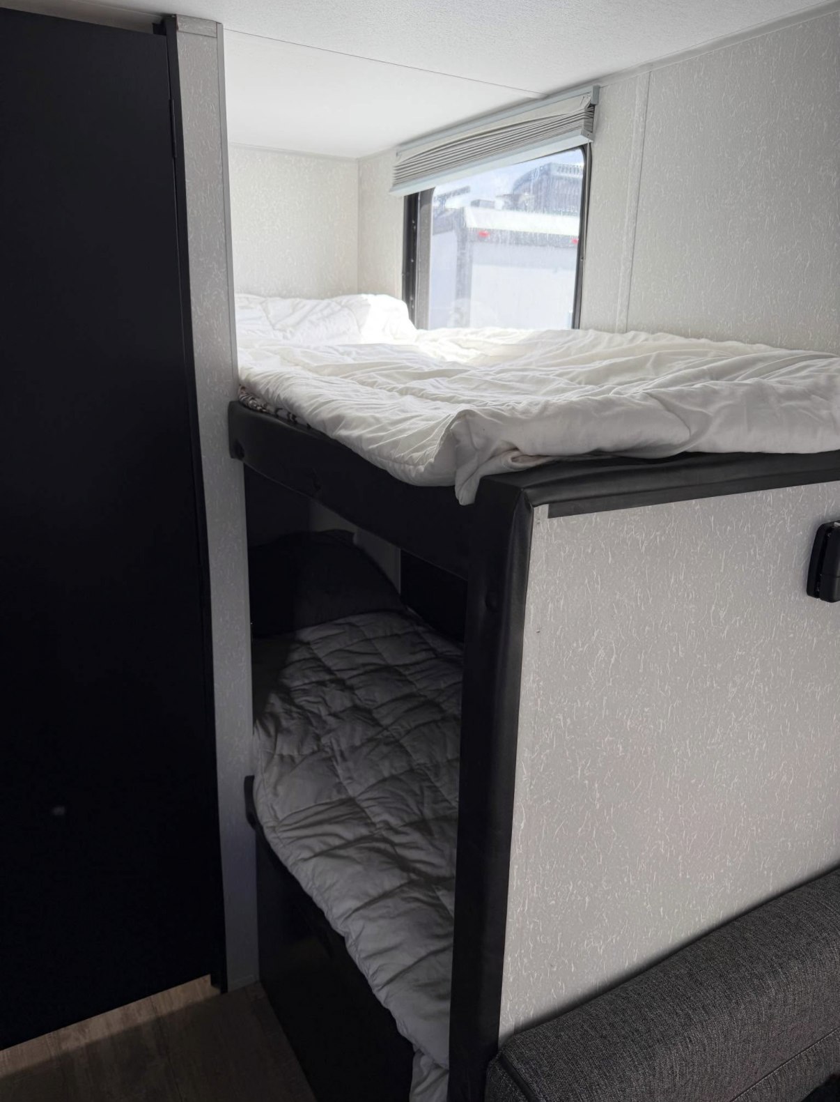 RV rental interior showing bunk beds. The upper bunk is bright with a window; the lower bunk is a darker, cozy sleeping area.. Forest River Cherokee Wolf Pup 2021