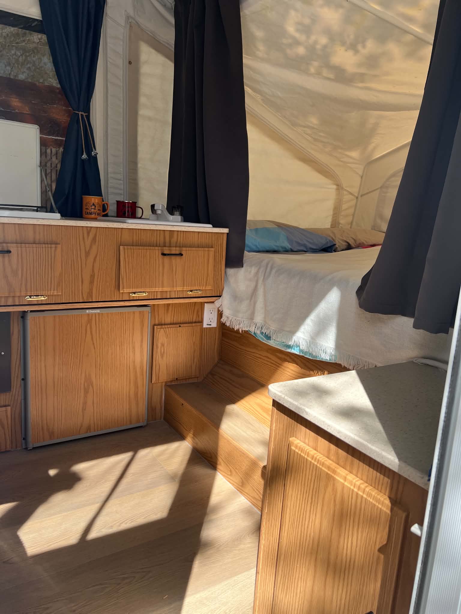 Cozy rv rental interior: light wood cabinetry, bed with pillows, and sunlit floors. Perfect for your next adventure!. Flagstaff Towing 2005