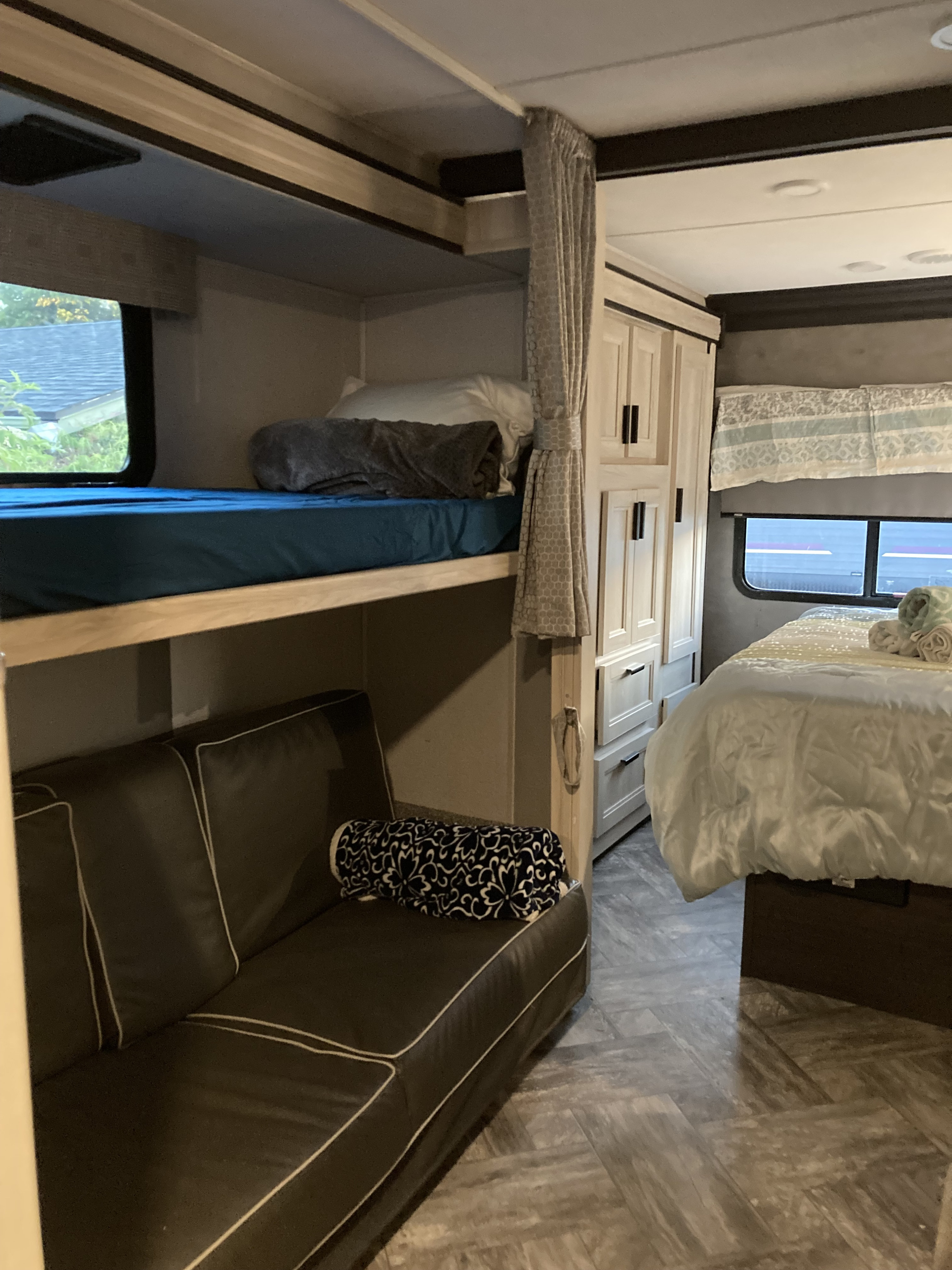 Inside an RV rental: bunk beds (top bunk, bottom sofa), main bed, and built-in storage cabinets. Ideal for a family trip.. Forest River Sunseeker LE 2022