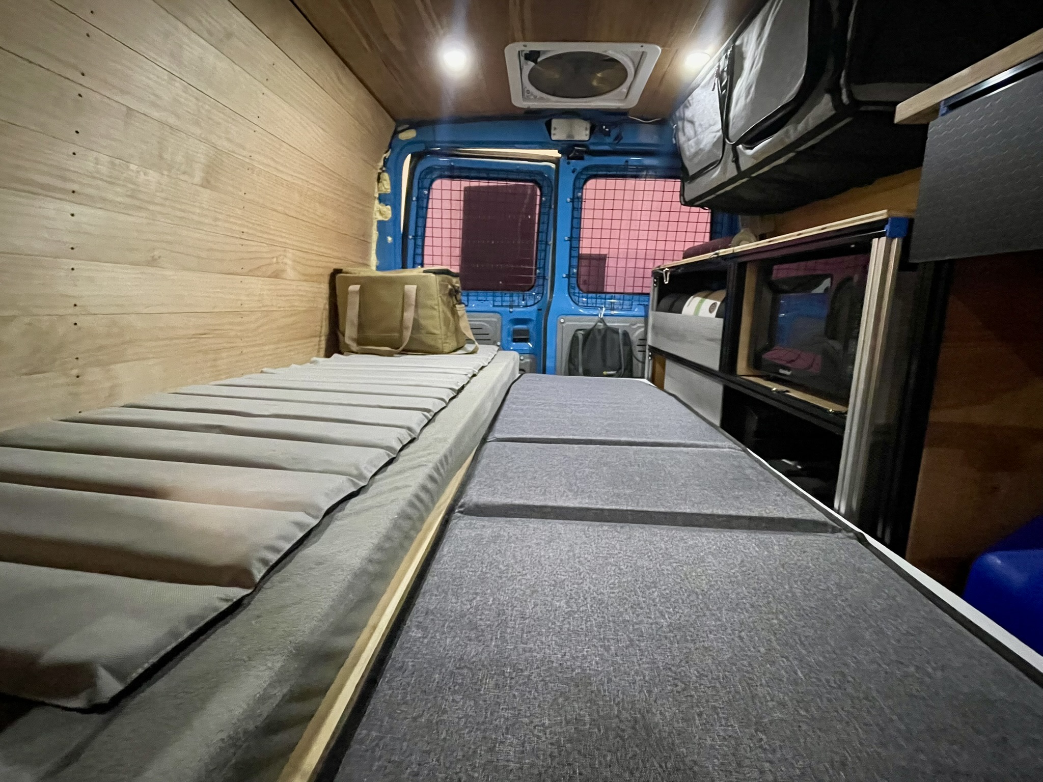 RV rental camper van interior: Two beds, wood walls, overhead storage, and rear cargo doors. Ready for your next adventure!. Ford E350 2010