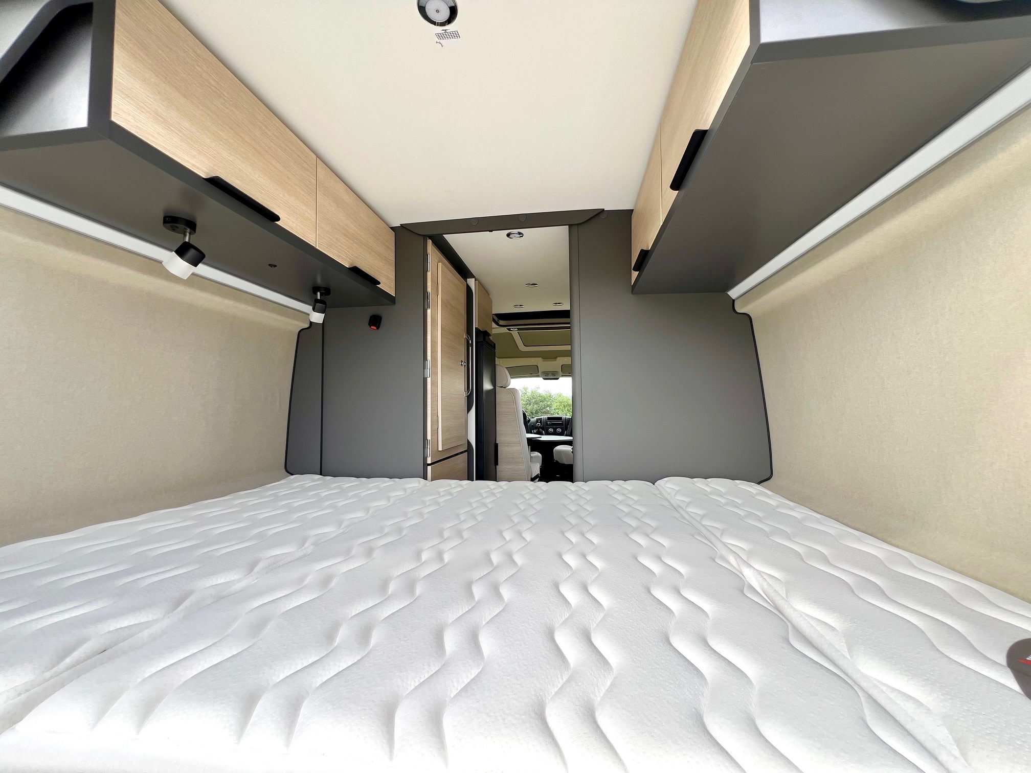 Experience comfort in this rv rental. Inside, a spacious campervan bedroom with a wide mattress, overhead storage, and a view to the front.. Peugeot Partner 2025