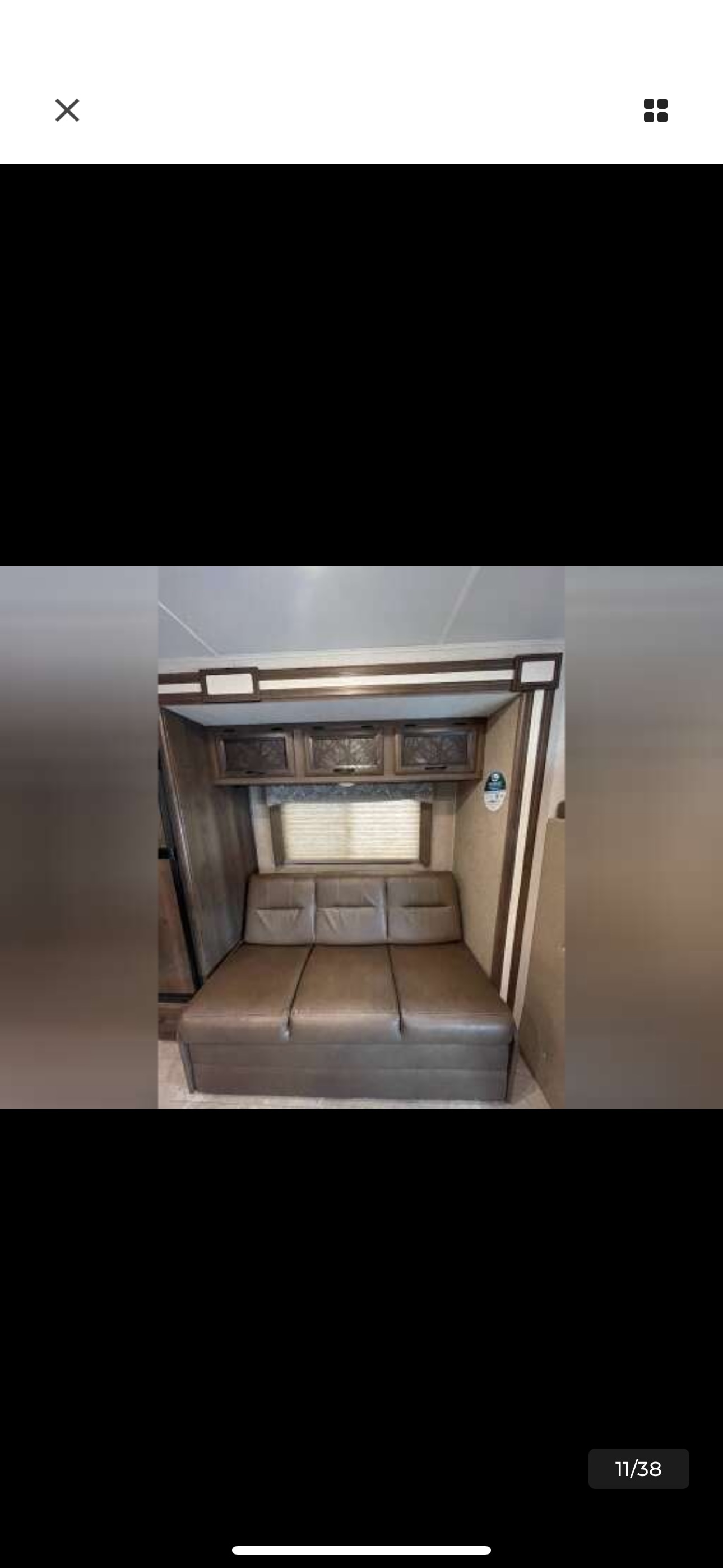 RV rental interior featuring a convertible brown sofa, window with blinds, and wooden overhead cabinets.. Coachmen Freelander 26DS 2019