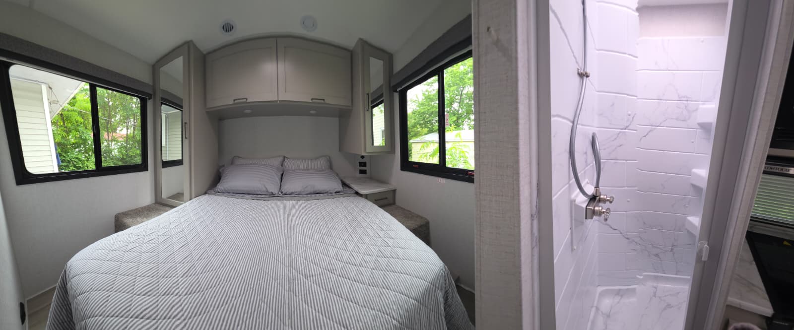 Modern RV rental interior: cozy bedroom with storage, bed & windows, plus a compact shower. Ideal for travel.. Thor Coleman 2026