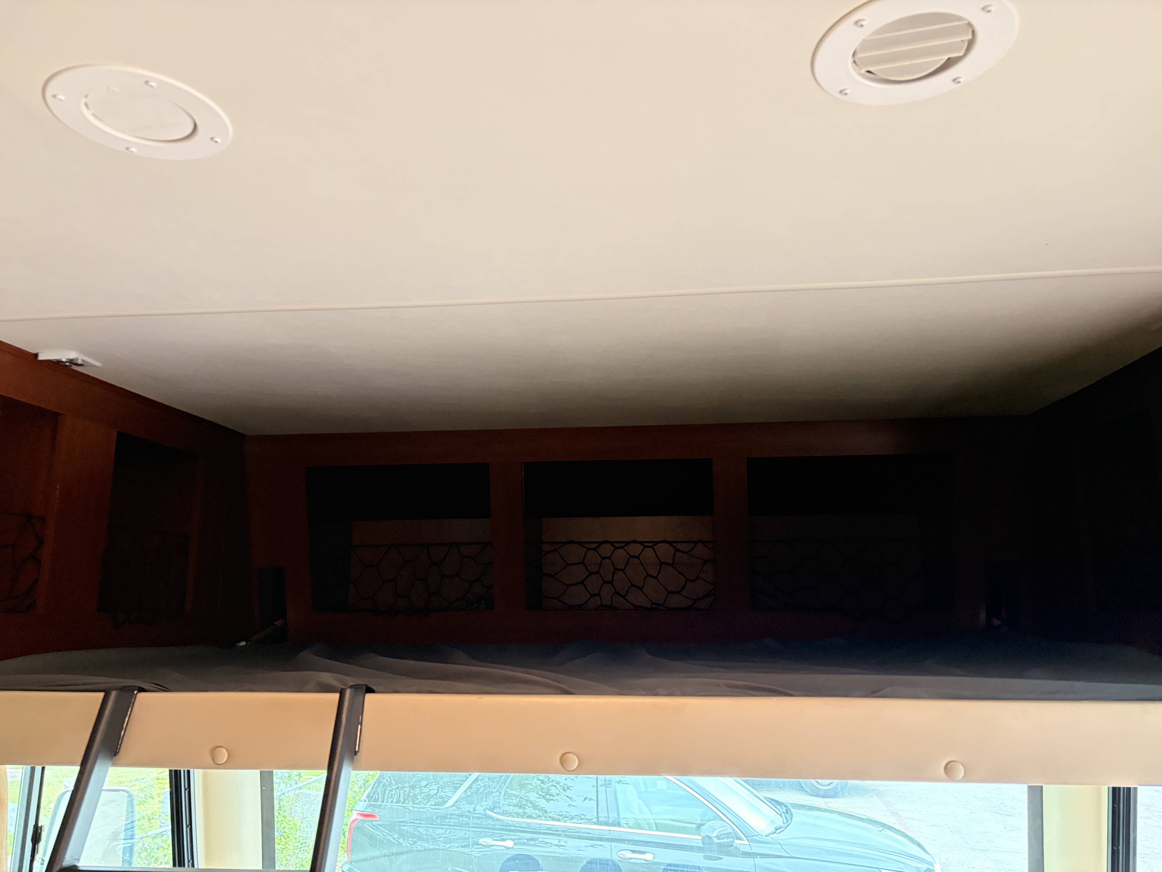 This RV rental shows a cozy overhead bunk with storage, ceiling vents, and a window view from the interior.. Thor Motor Coach A.C.E 2015