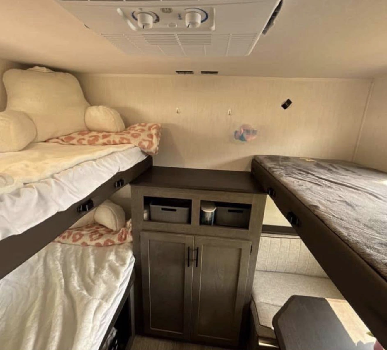 RV rental interior: two-tier bunk beds on left, storage in center, single bunk over dinette on right. AC unit overhead.. Forest River Cherokee Alpha Wolf 2025