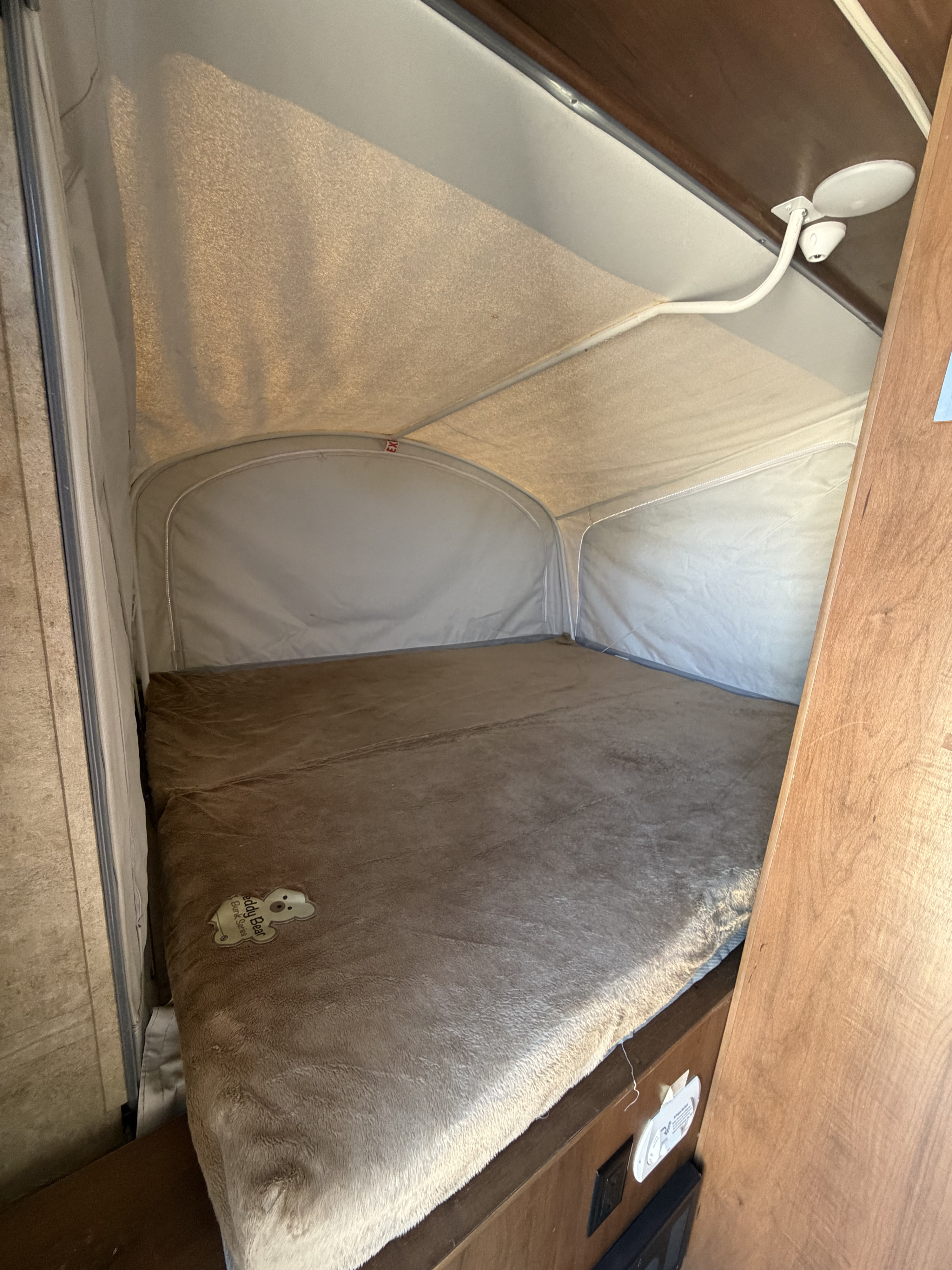 This RV rental's pop-up sleeping area features a large bed with a soft, brown Teddy Bear blanket and canvas walls.. Jayco Jay Feather 2017