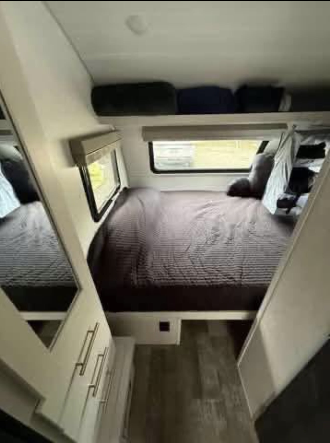 RV rental bedroom with a comfy dark bed, two windows, overhead storage, and mirrored wardrobe for your travels.. R-Pod Hood River Edition 2021