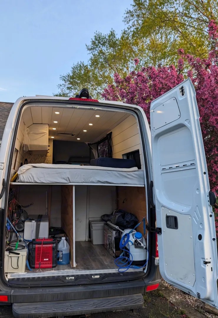 Inside a customized rv rental campervan, featuring a raised bed over organized storage for adventure gear, including power & water.. Mercedes Sprinter 2018