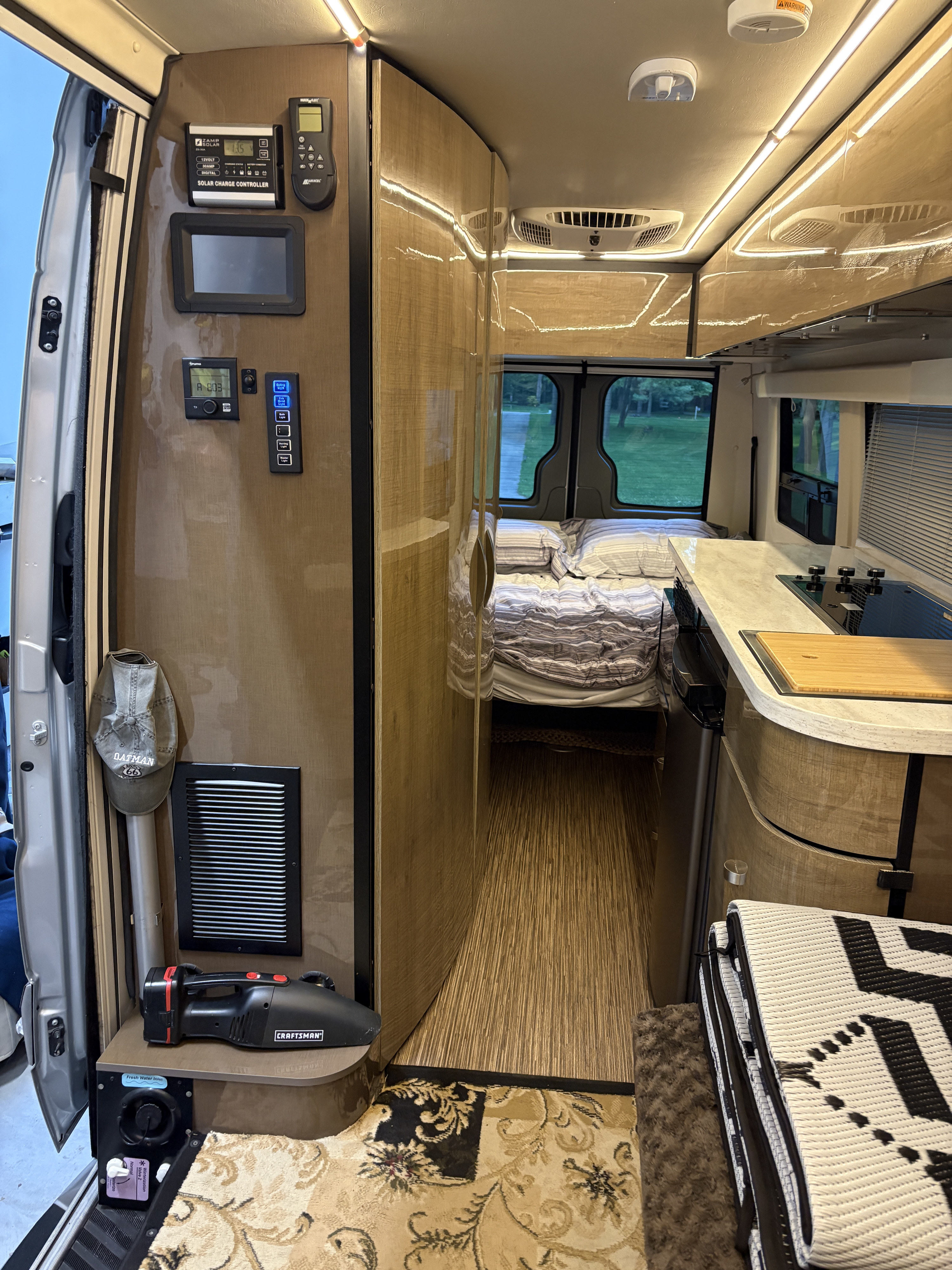 The interior of this RV rental shows a compact kitchen, bed, and control panel, designed for efficient mobile living.. Winnebago Era 2017