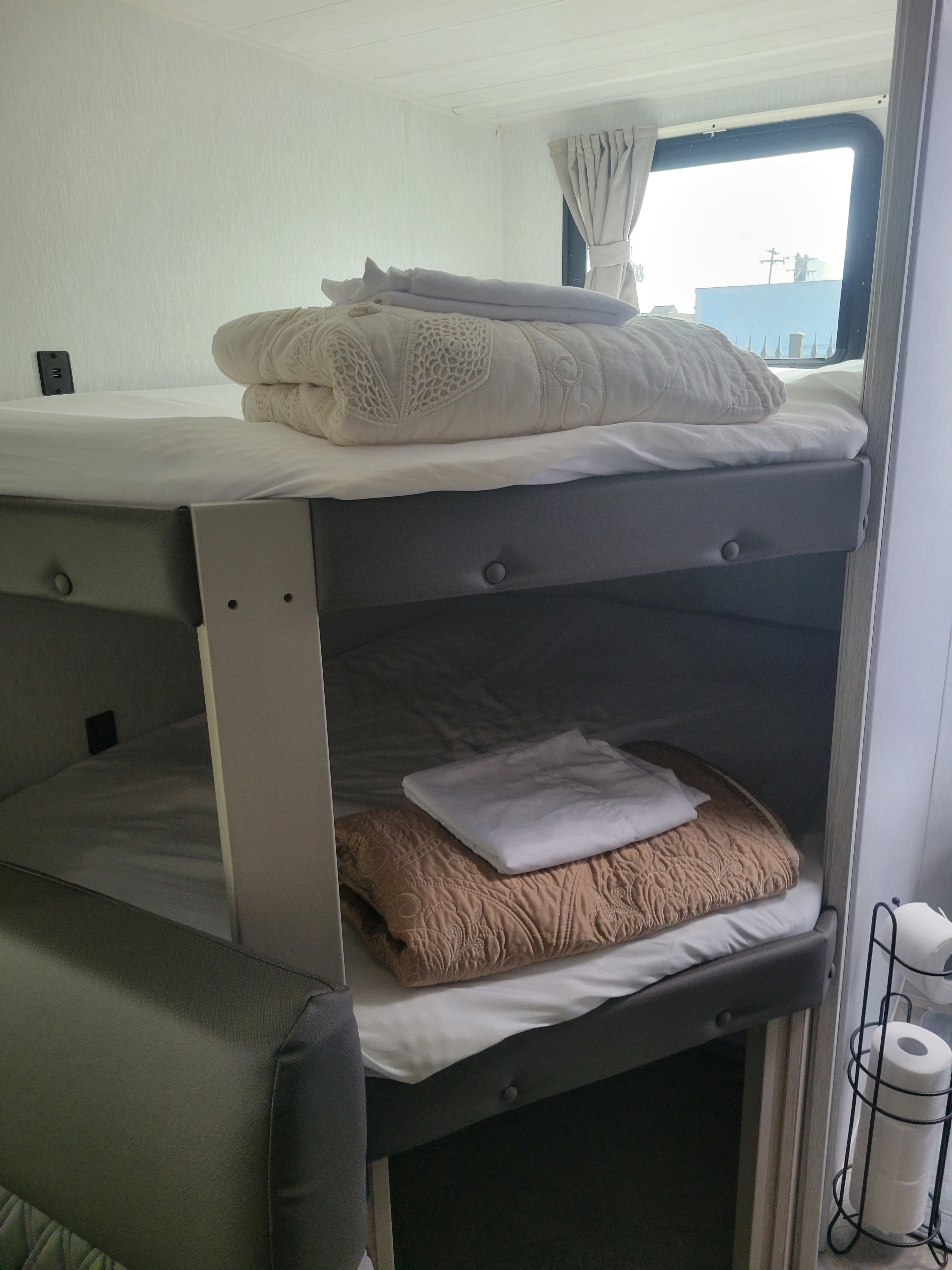 Two compact bunk beds with fresh bedding are ready in this bright rv rental, featuring a window and USB outlet.. Forest River Salem Cruise Lite 2023