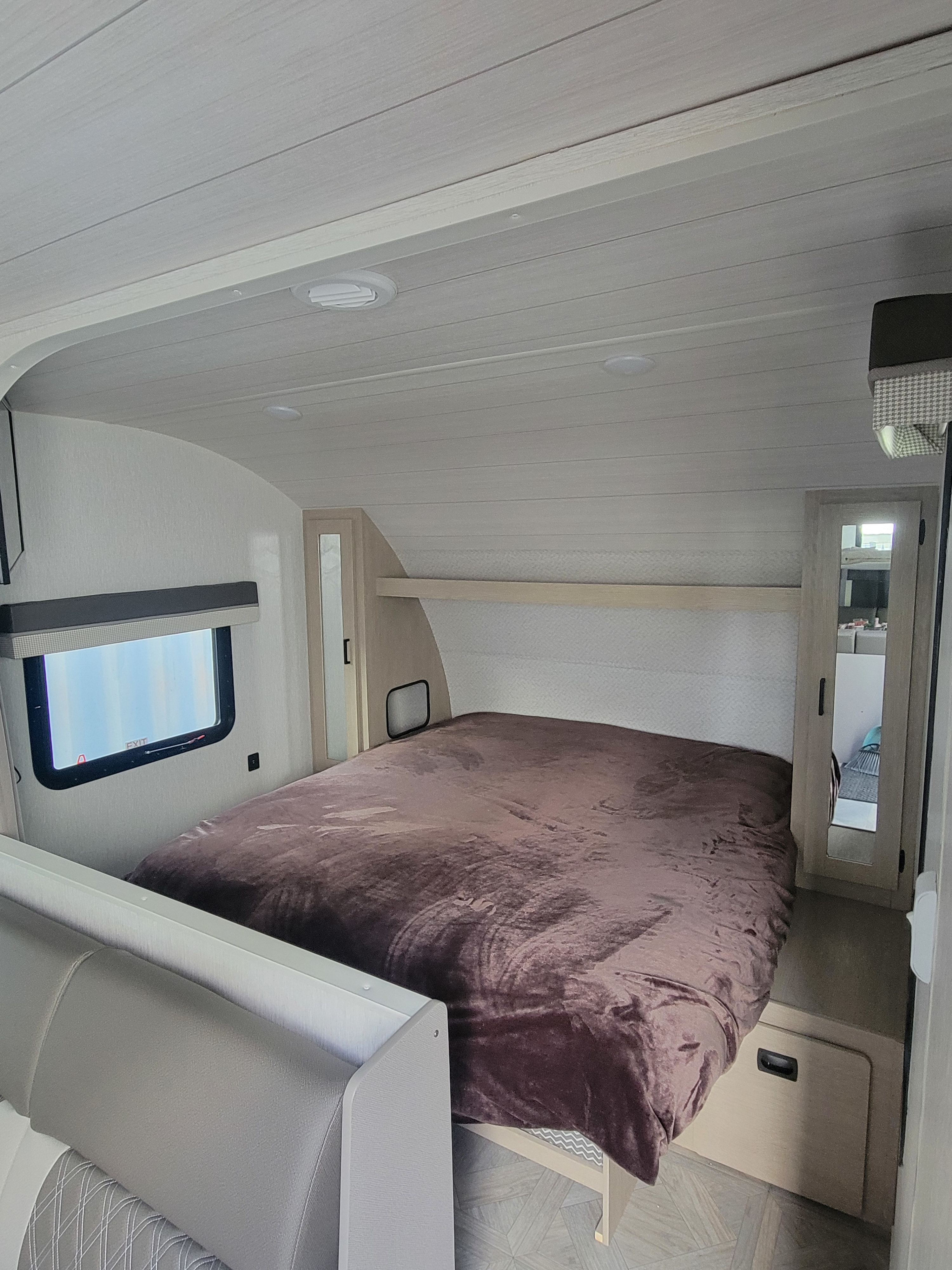 Comfortable RV rental bedroom with a brown-covered bed, window, and built-in storage. Ideal for travelers seeking cozy accommodations.. Forest River Salem Cruise Lite 2023