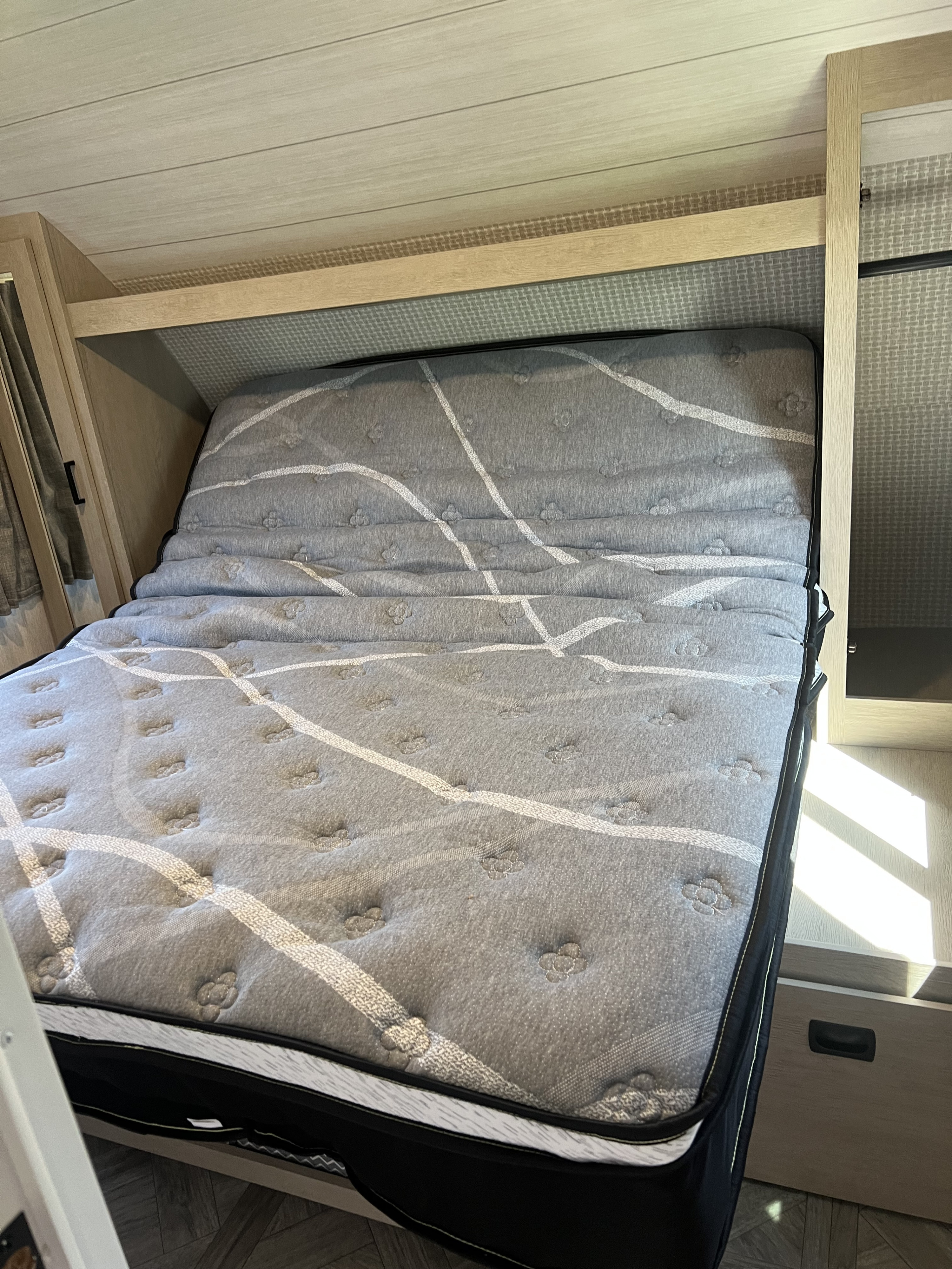 Comfortable gray patterned mattress in an RV rental bedroom, featuring light wood paneling and cabinetry.. Forest River Salem Cruise Lite Platinum 2024