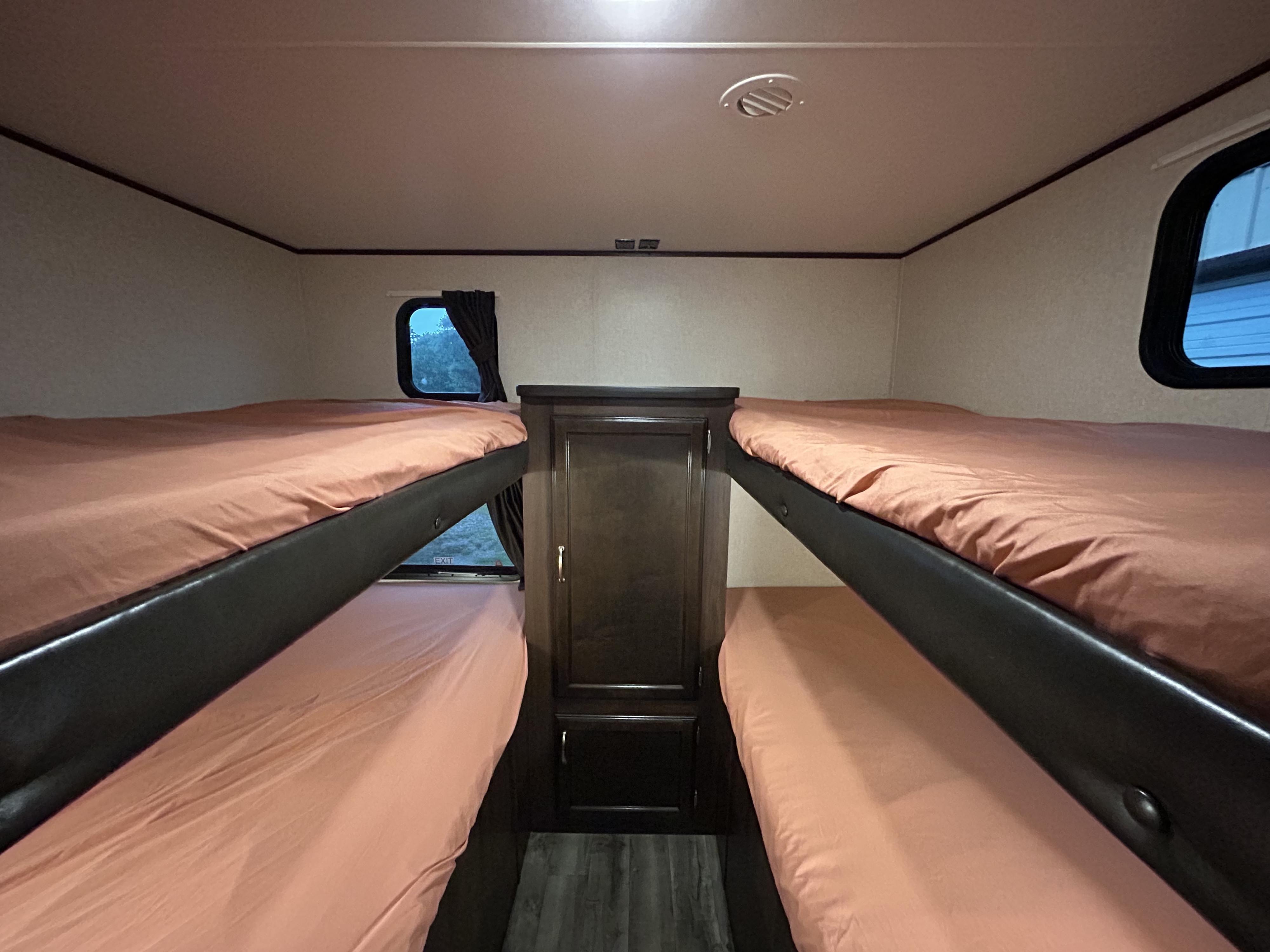 This RV rental's bunk bed area features peach-colored sheets on dual bunks flanking a central storage cabinet.. Jayco Jay Flight SLX 2018