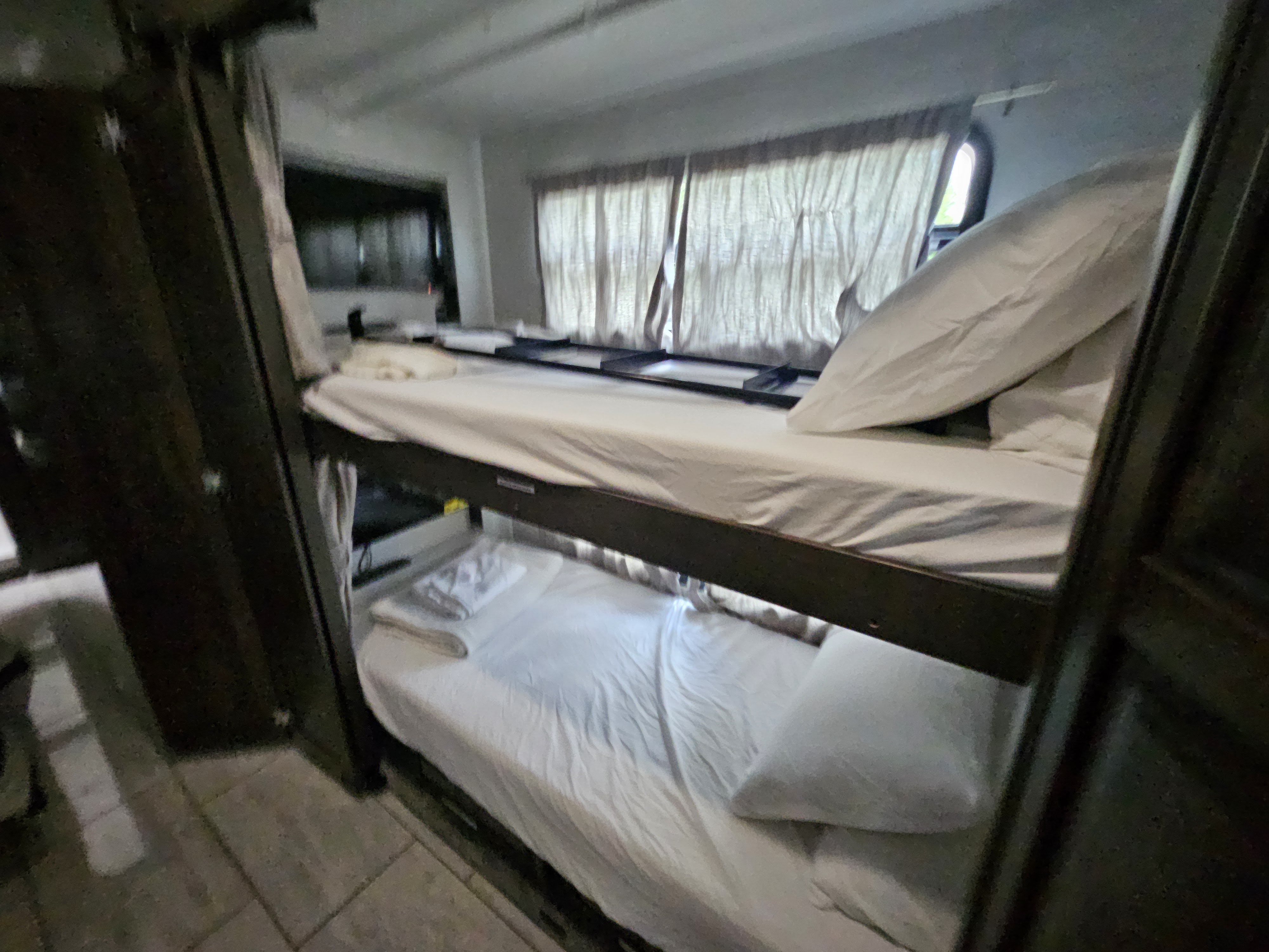 Cozy RV rental bunk beds: fresh white linens provide compact sleeping accommodations for your adventure.. Forest River Berkshire XLT 2024