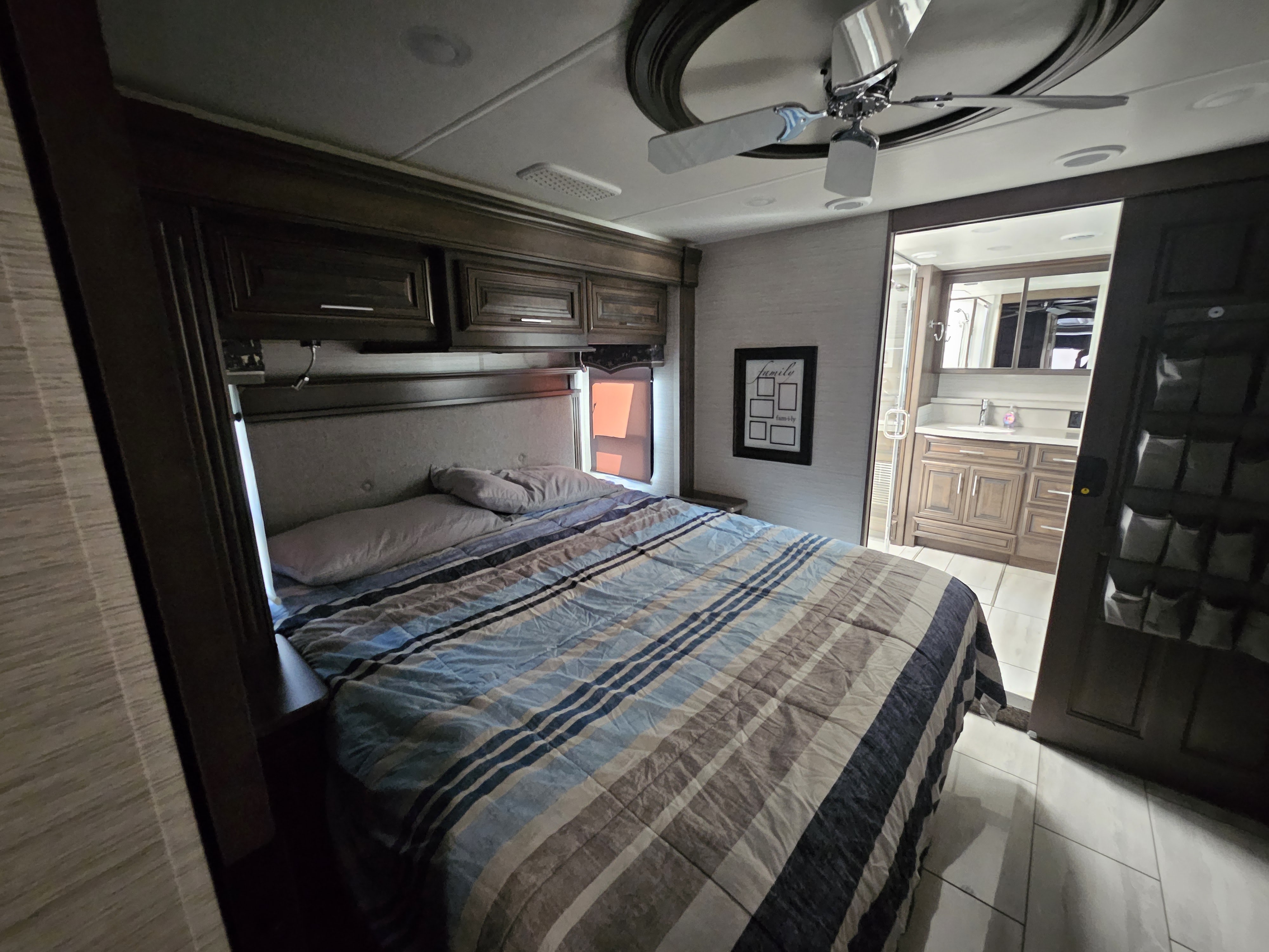 Spacious RV rental bedroom with cozy bed, overhead storage, ceiling fan, and adjacent bathroom.. Forest River Berkshire XLT 2024