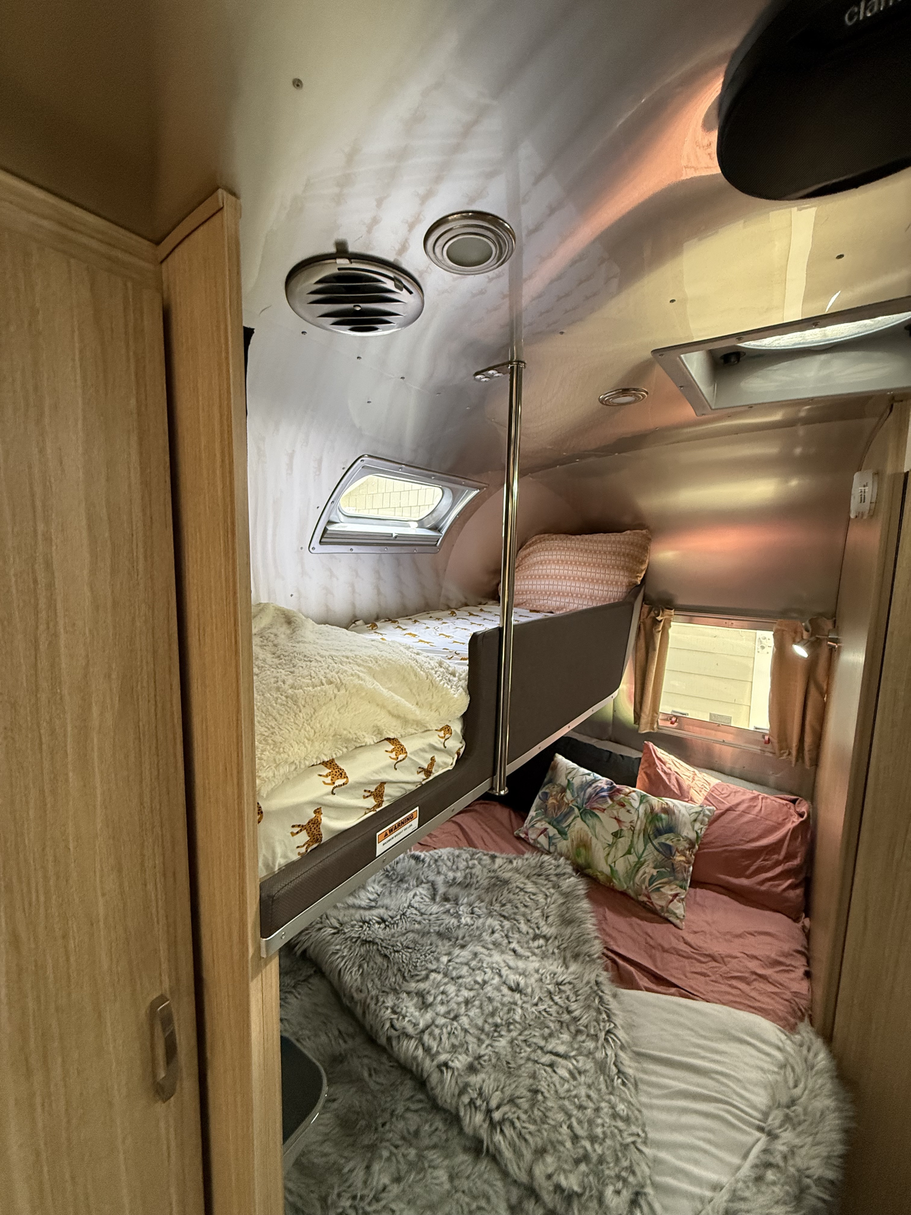 Cozy RV rental interior: bunk beds with cheetah print & soft blankets, offering comfortable sleeping quarters.. Airstream Flying Cloud 2018