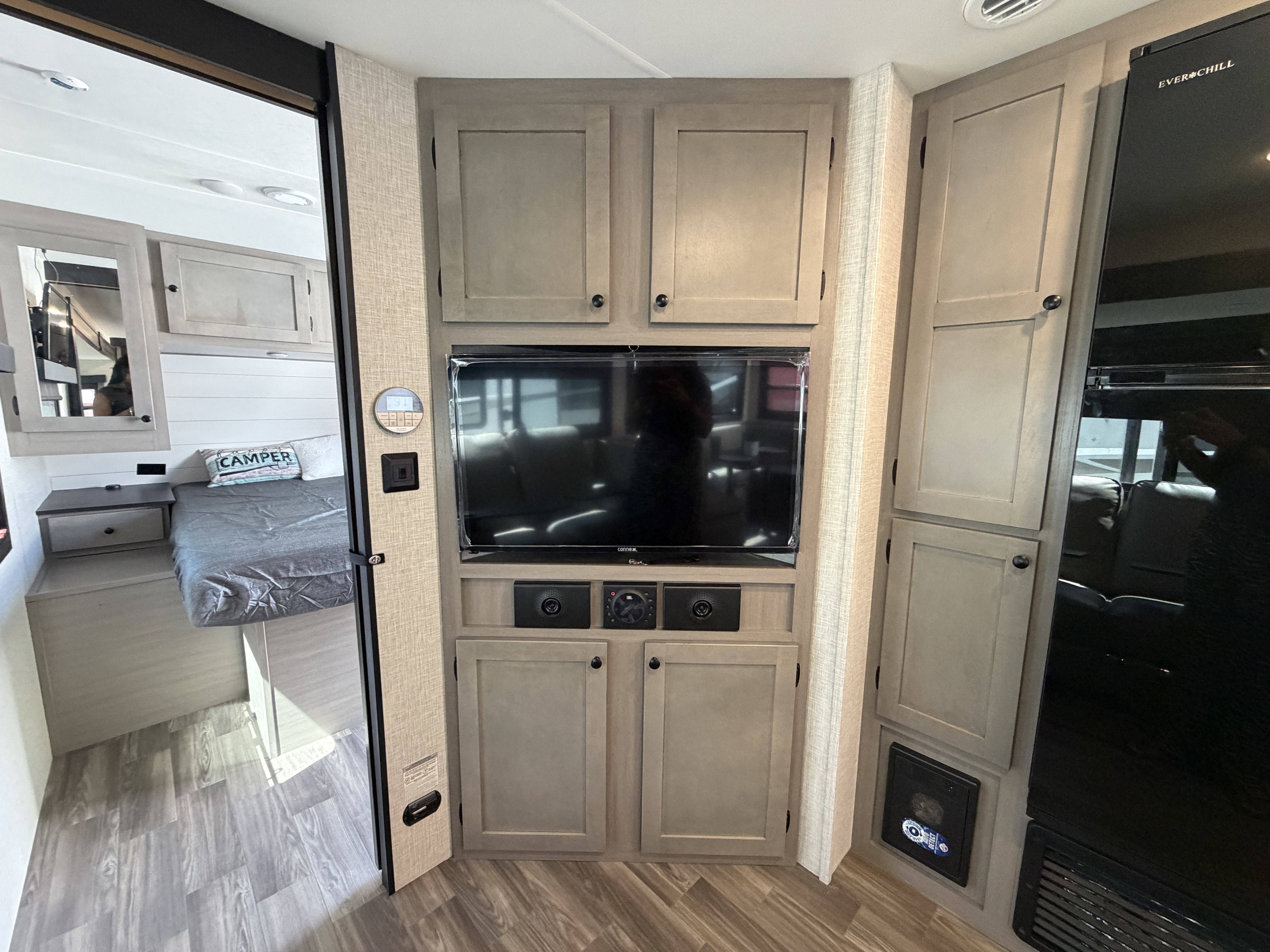Modern rv rental interior: bedroom view, central entertainment unit, and kitchen fridge/storage.. Starcraft Super Lite 2024
