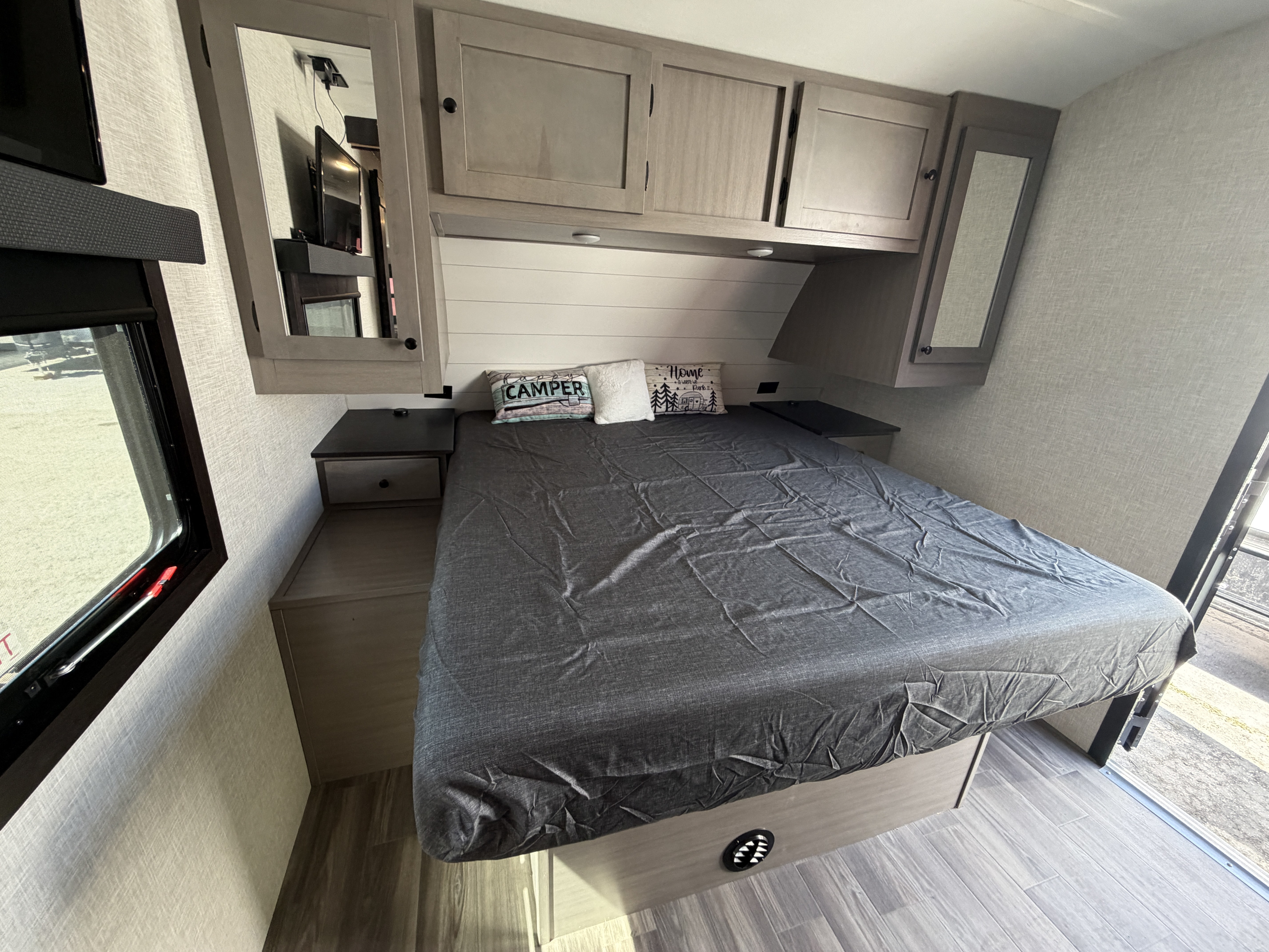 This RV rental bedroom offers a cozy bed, ample overhead cabinets, and natural light from the window, ideal for road trips.. Starcraft Super Lite 2024
