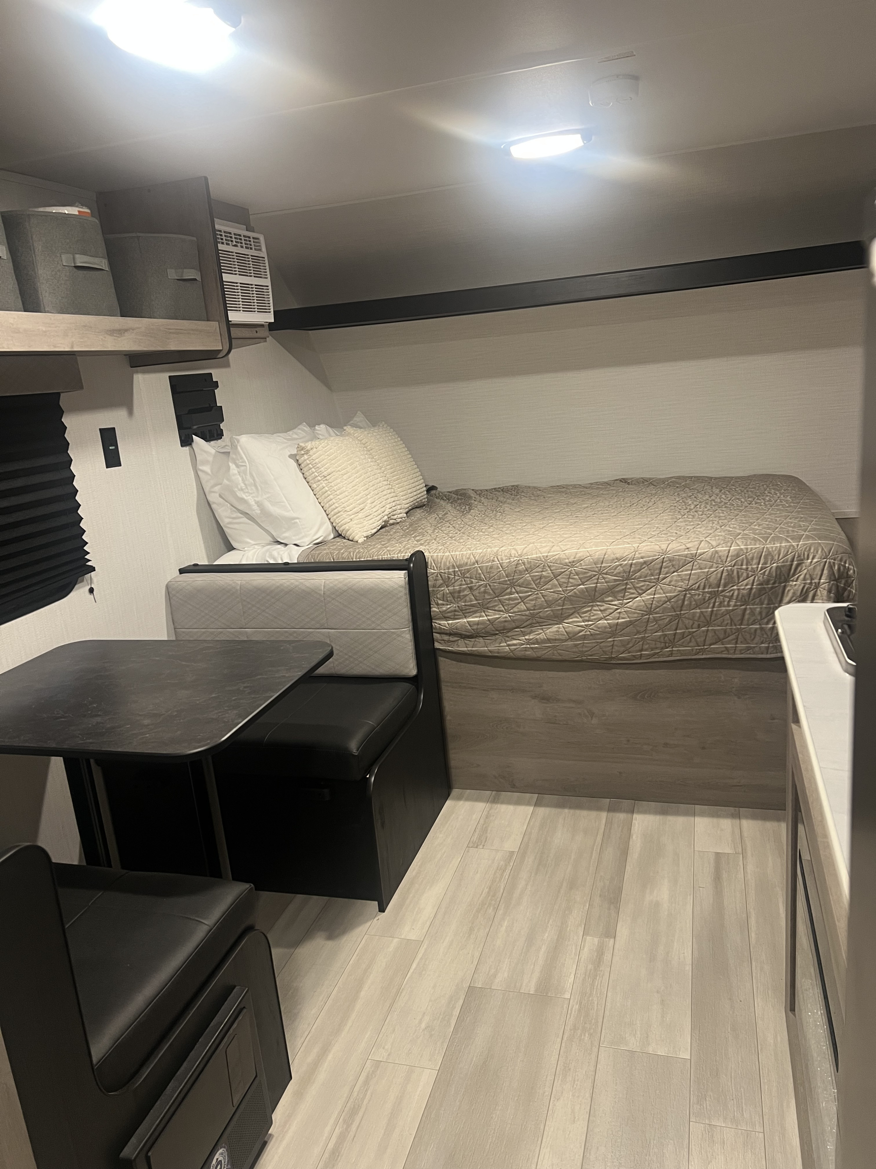 Cozy RV rental interior with a comfortable bed, dinette, overhead storage, and modern wood-look flooring.. Heartland Prowler Lynx 17BHX 2025