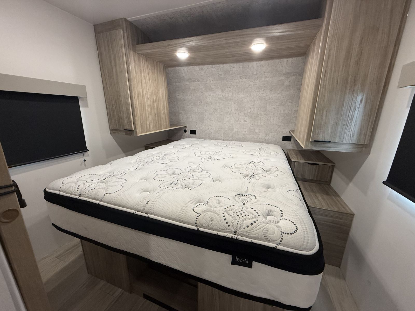 Modern RV rental bedroom featuring a comfortable hybrid mattress, built-in wooden cabinetry, and overhead lighting for a cozy stay.. Winnebago Access 2024
