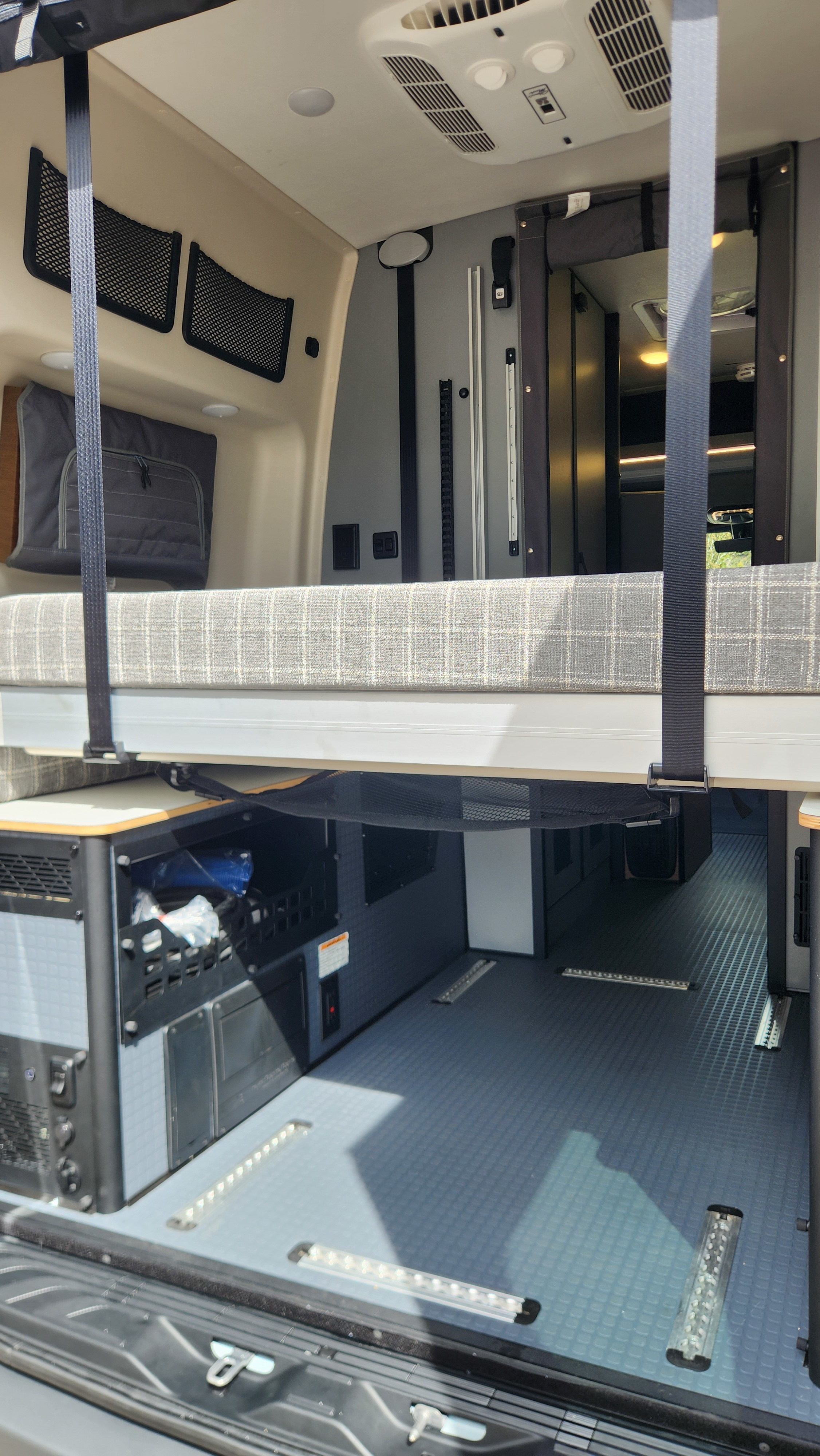 RV rental camper van interior featuring a raised bed, spacious cargo area, integrated power system, and overhead storage.. Winnebago Revel 2026