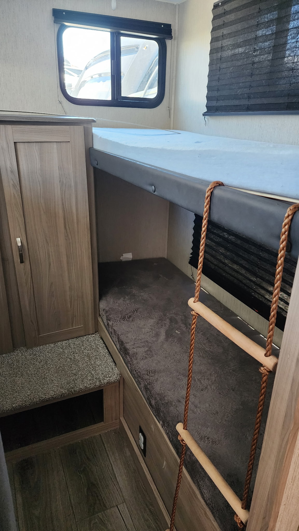 This RV rental features bunk beds with a rope ladder, a window, and a wardrobe, providing comfortable sleeping and storage.. Coachmen 292bhs 2021