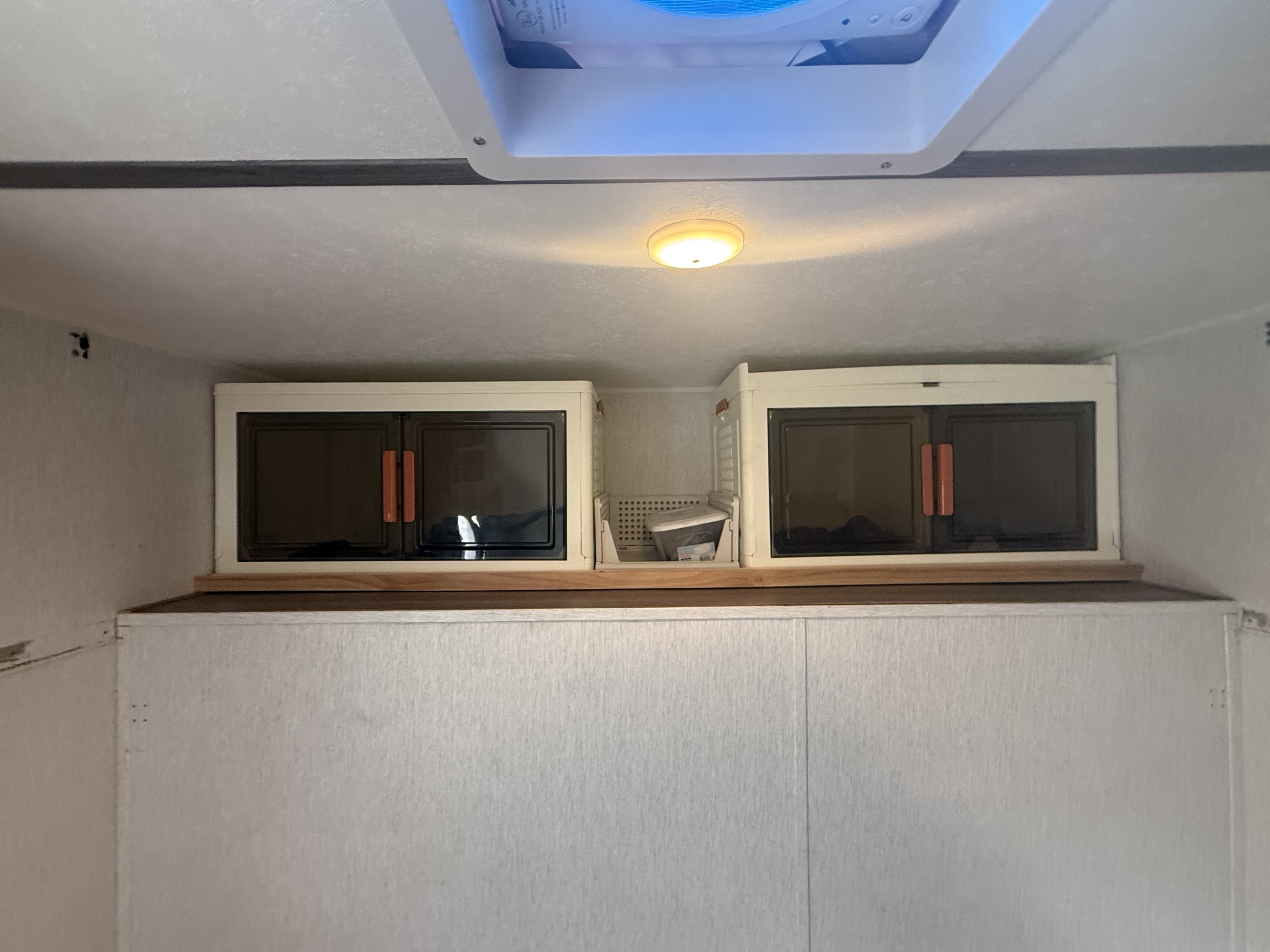 Interior of an RV rental with two overhead storage cabinets, a ceiling light, and vent, for organized travel.. Sunset RV park Sunray 129 2025