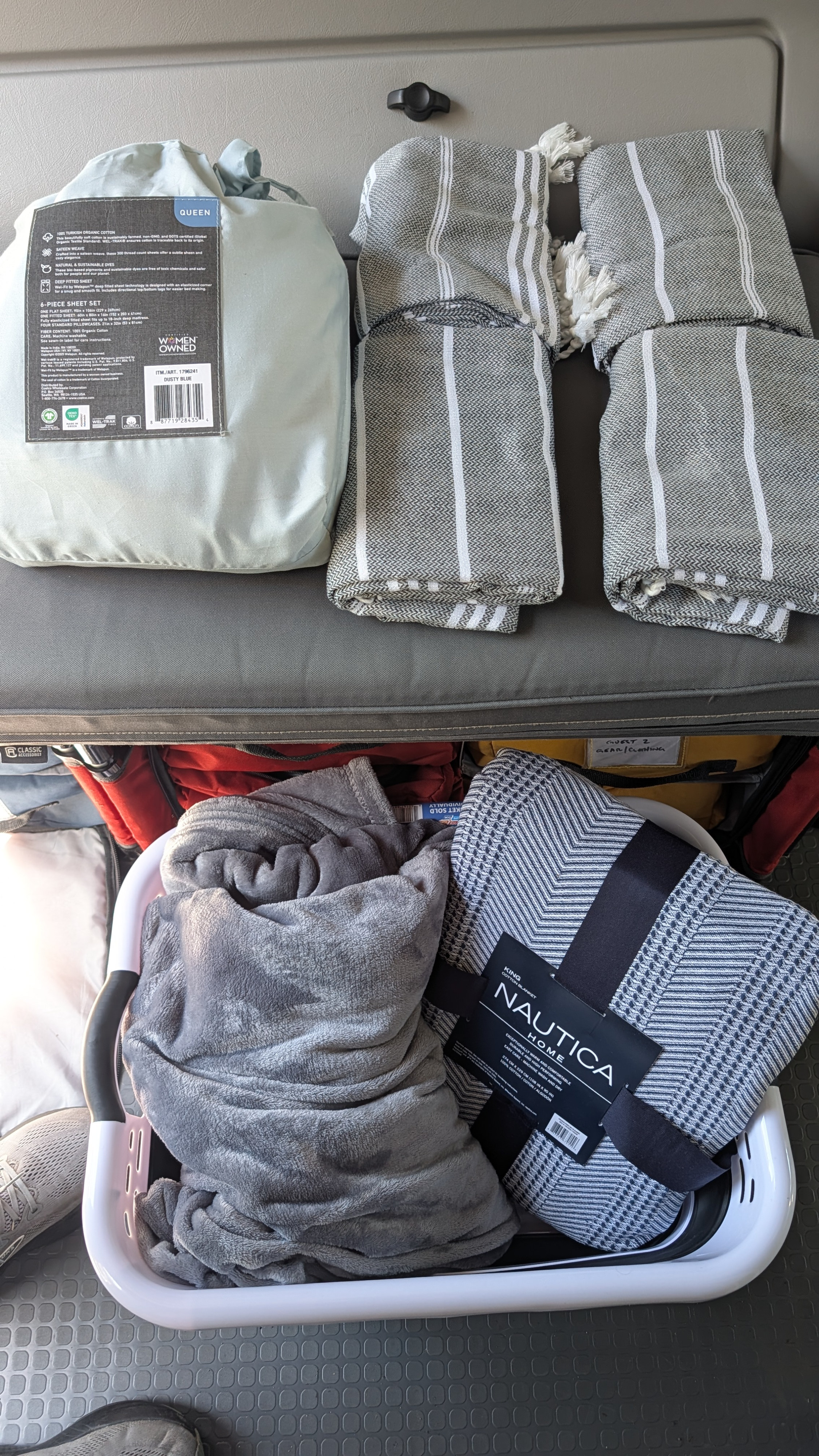 Preparing an RV rental with cozy bedding: a queen sheet set, striped blankets, and a plush blanket for travel comfort.. Winnebago Revel 2023