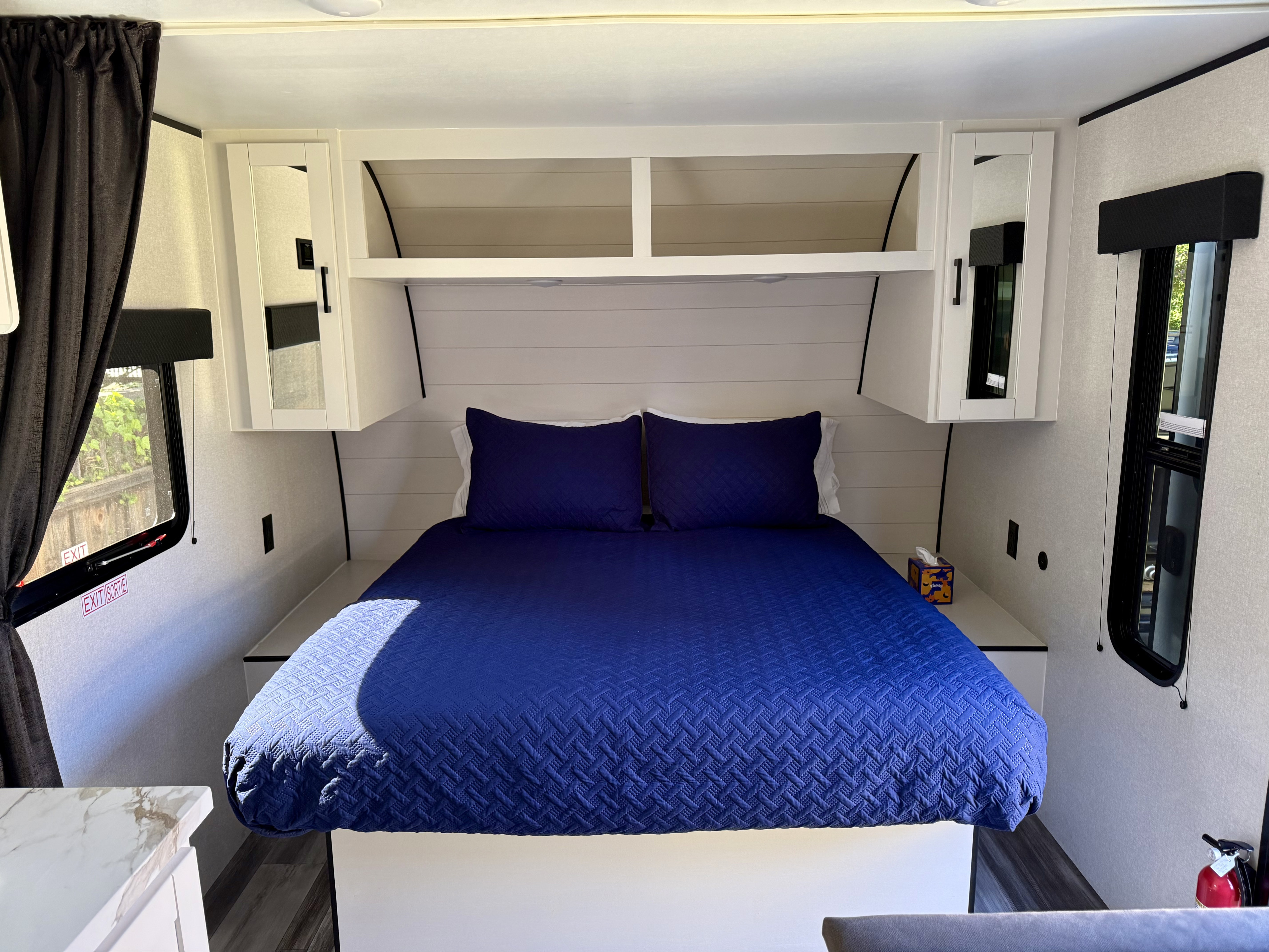 Modern RV rental bedroom: blue quilted bed, shiplap, mirrored cabinets, storage, and windows.. Jayco Jay Flight SLX 175 FQW Baja 2026