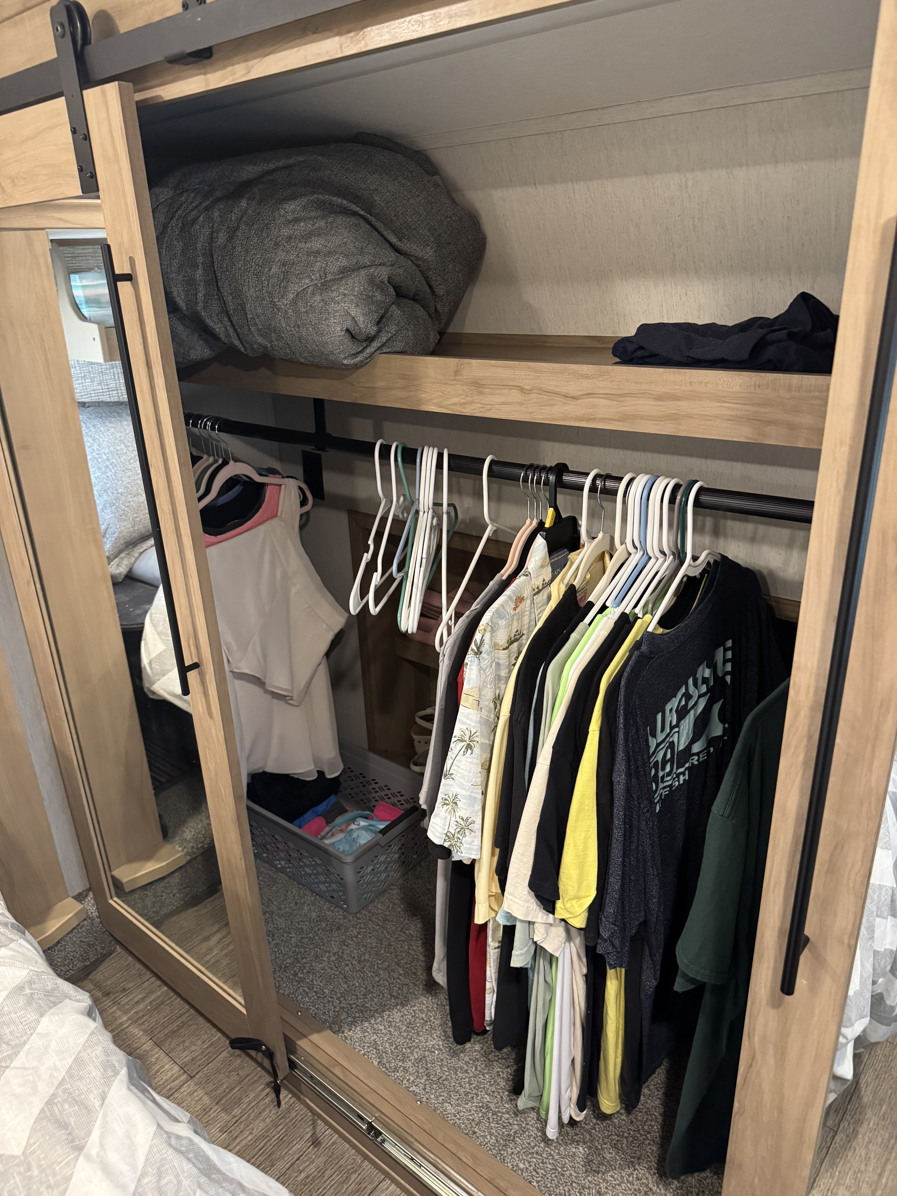 RV rental: Mirrored closet door reveals hanging clothes, shelf storage with blanket, and a laundry basket inside.. Forest River Sabre 2023