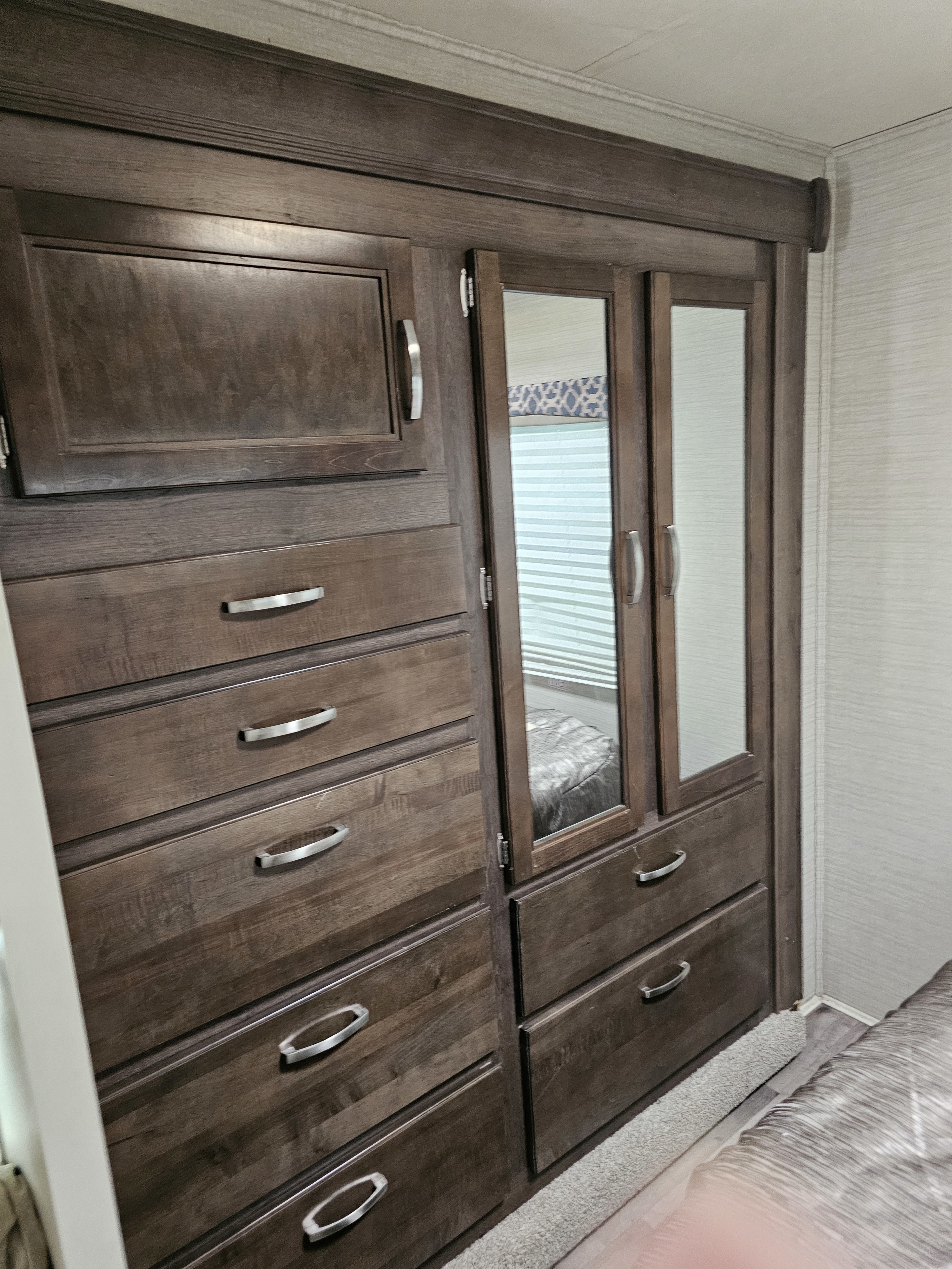 RV rental bedroom storage: dark wood dresser and mirrored wardrobe with multiple drawers, ideal for compact living.. Jayco Redhawk 2019