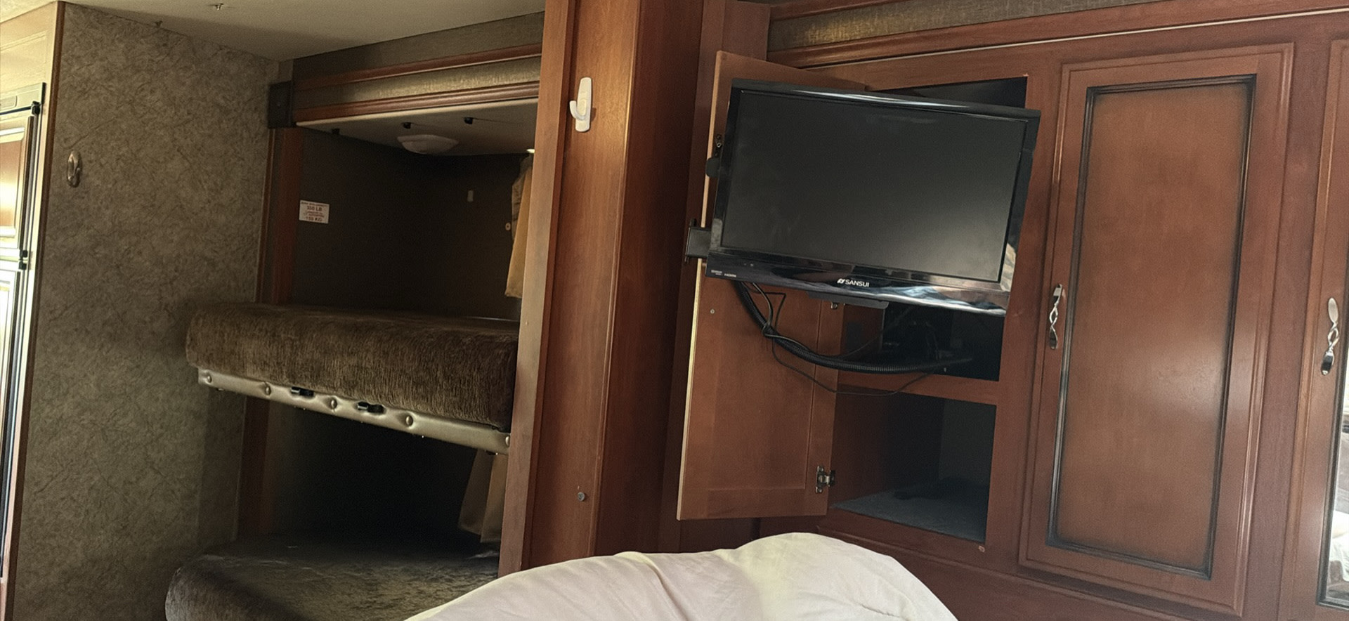 Cozy RV rental interior with bunk beds, a mounted TV, and storage cabinets, ideal for family trips.. Fleetwood 31C 2015