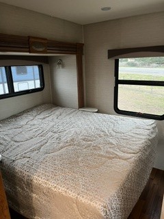 Spacious RV rental bedroom featuring a large bed and windows, offering comfortable travel accommodations for your journey.. Jayco Greyhawk 2017