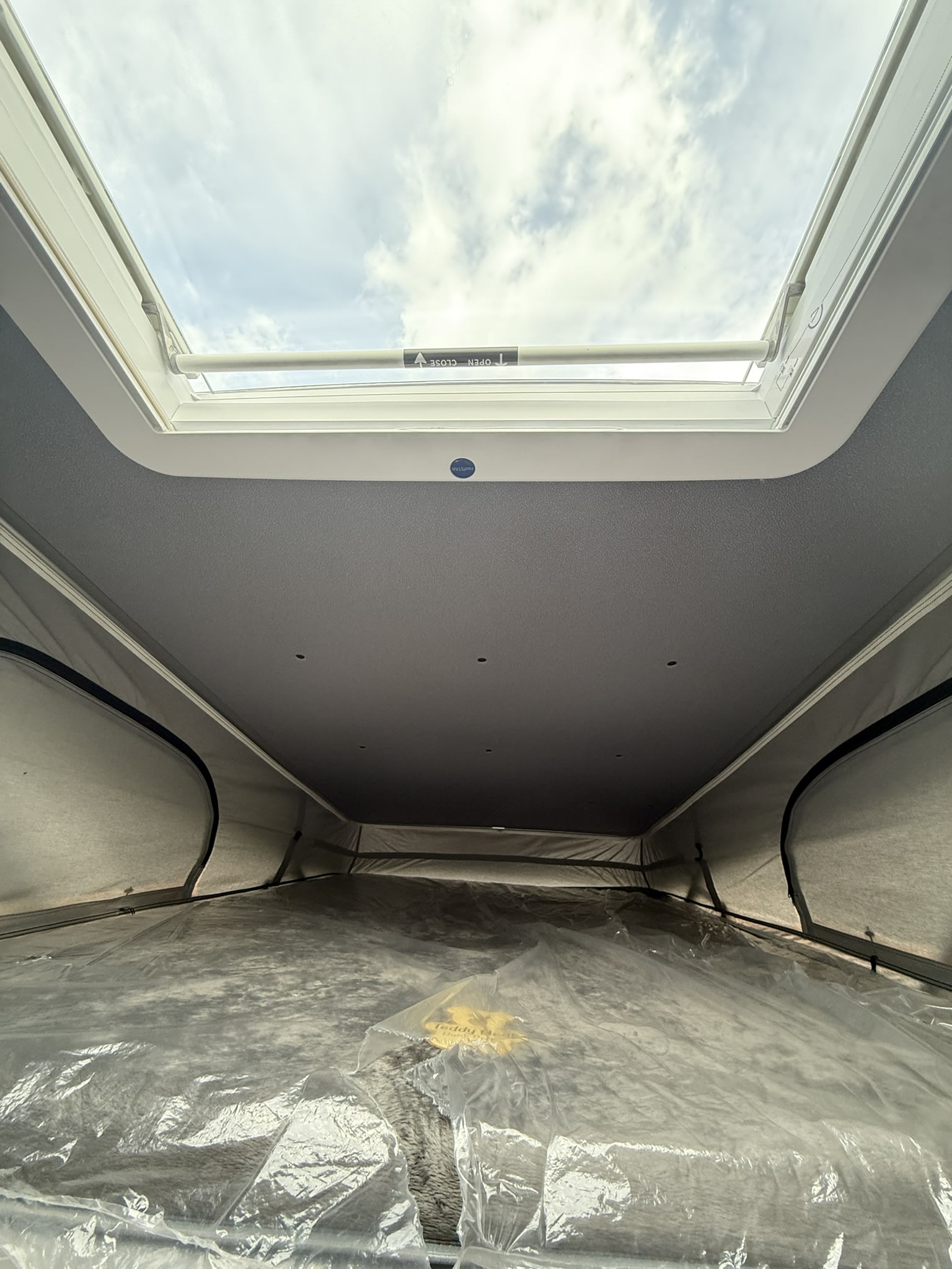 RV rental pop-top interior: A protected, spacious bed beneath an open skylight, offering bright views for your journey.. Coachmen Nova 2024