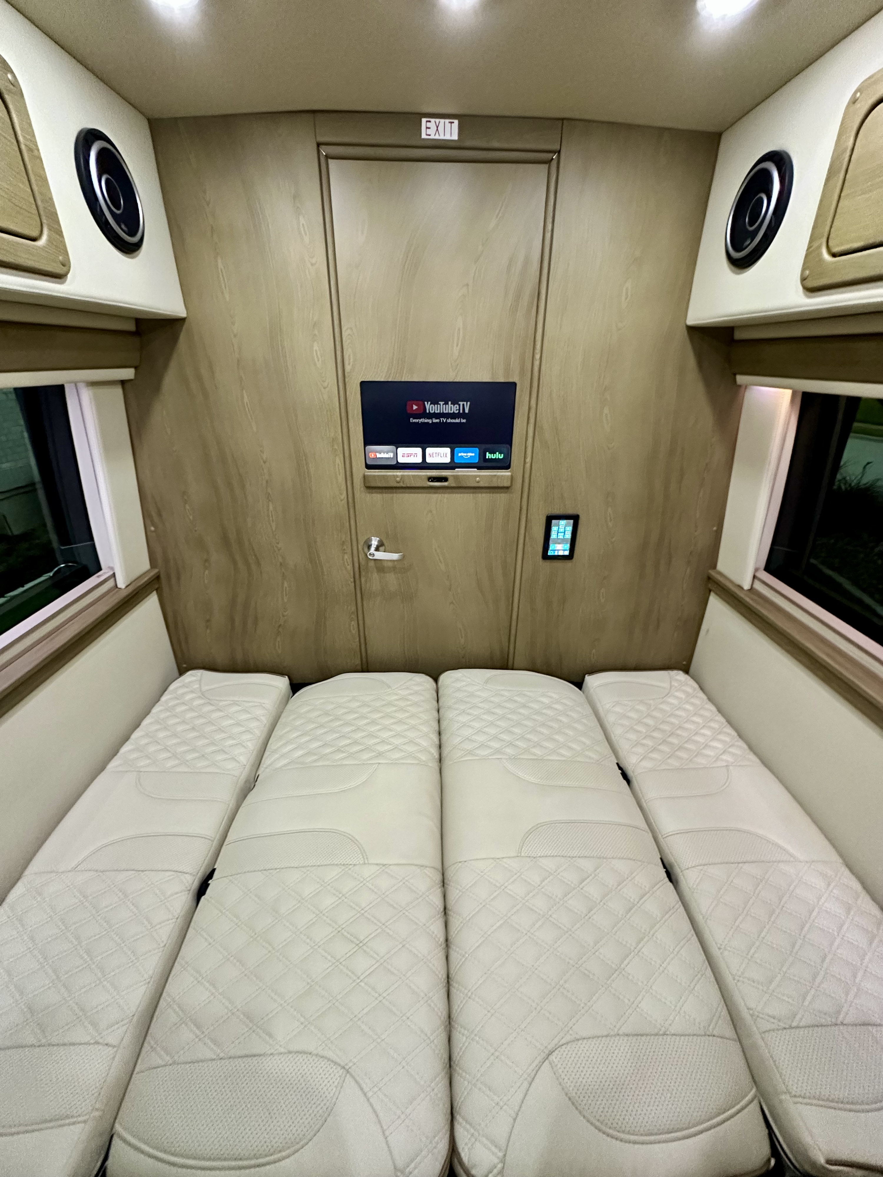 Spacious rv rental interior showing four white quilted beds, a smart TV with streaming, and control panel. Comfortable travel van setup.. Midwest Automotive Designs Day Cruiser Luxe 2022