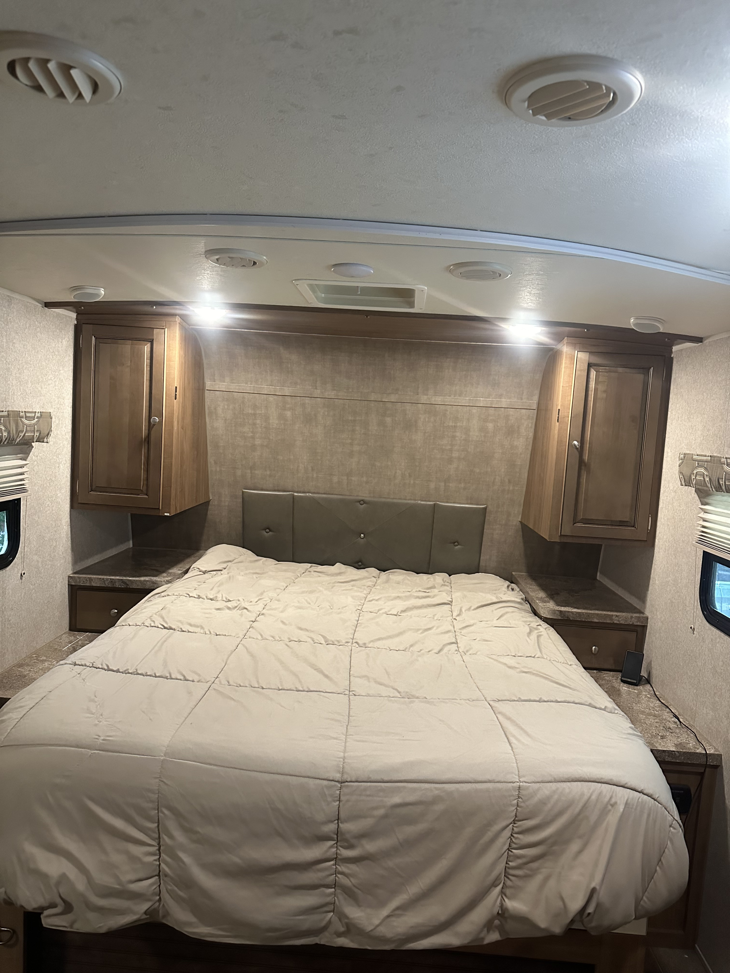 Cozy RV rental bedroom with a comfortable bed, padded headboard, and integrated storage, perfect for a relaxing travel interior.. Forest River Flagstaff Micro Lite 2017