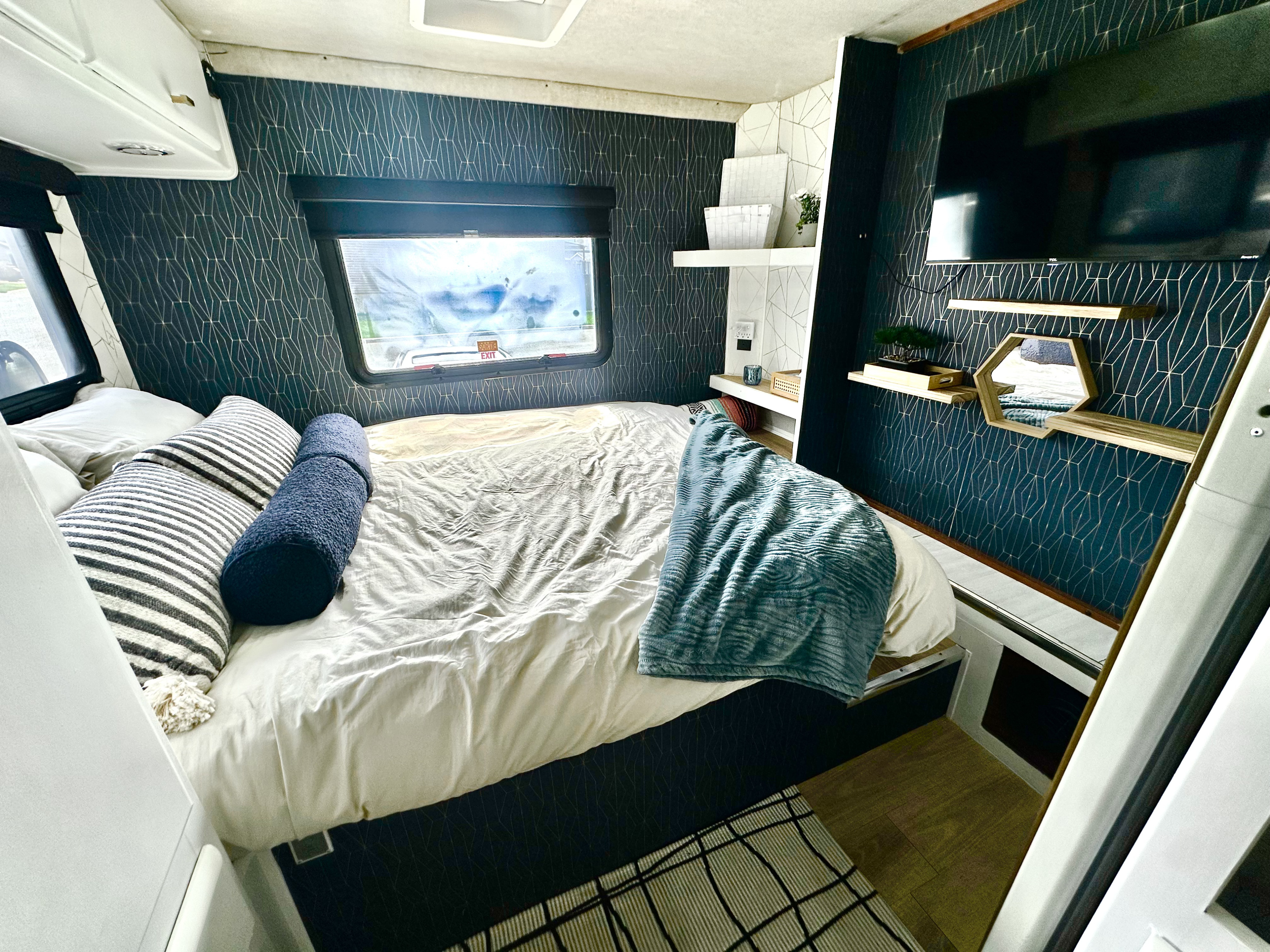 Experience modern comfort in this cozy rv rental bedroom with geometric walls, a plush bed, and functional decor.. Jamboree Sport 2009