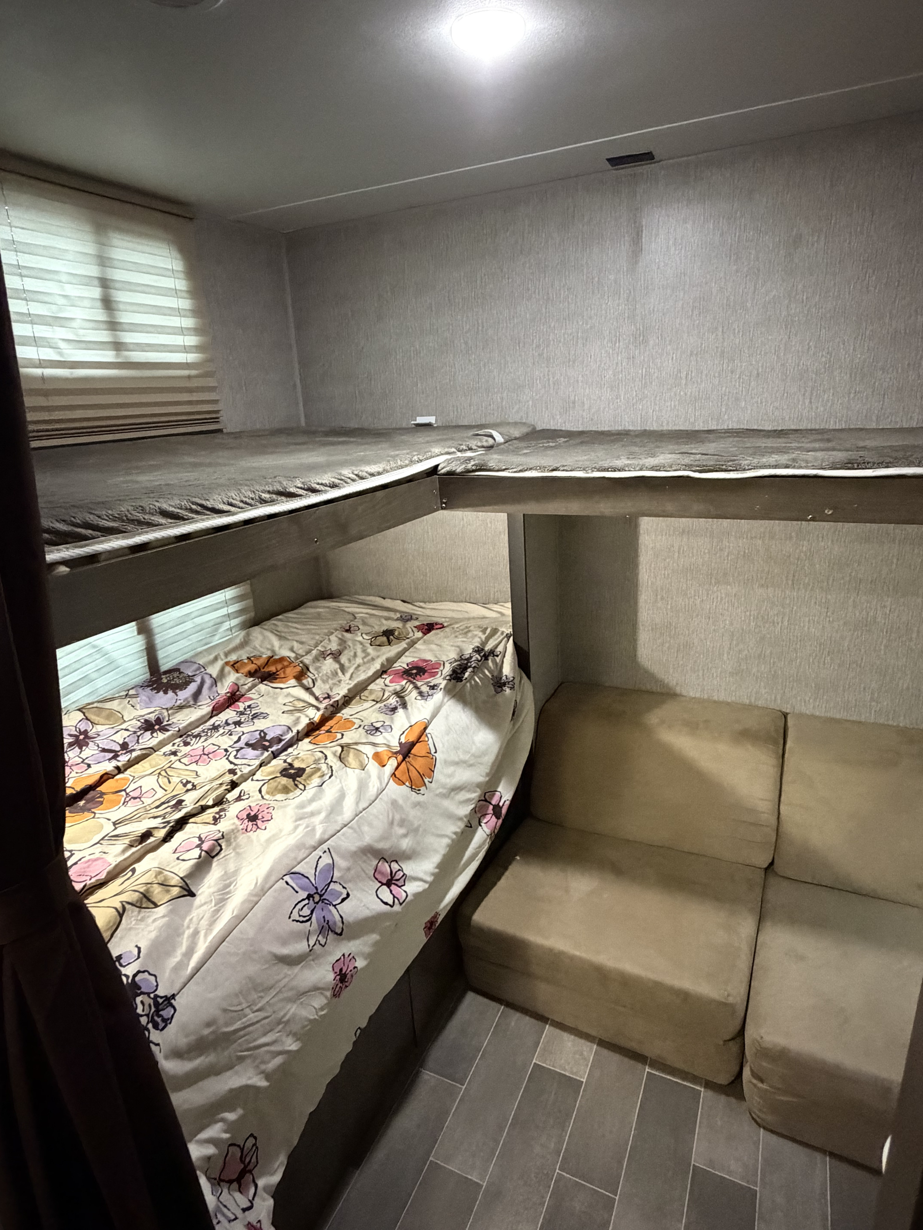 RV rental sleeping area featuring bunk beds (floral lower bunk) & compact beige sofa. Cozy, functional interior.. Coleman 295QB 2019